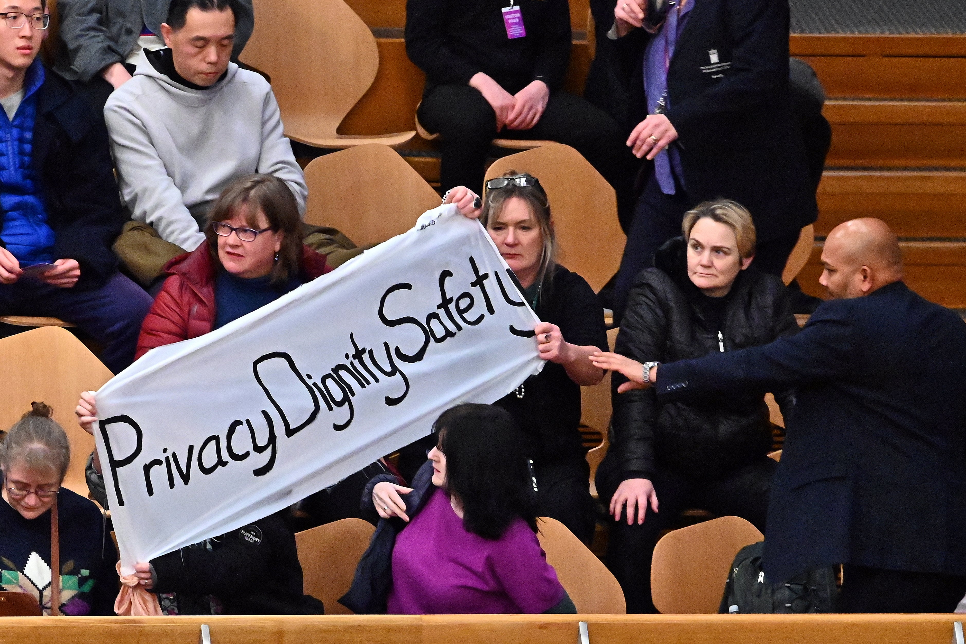 Protesters display a banner in the public gallery of the Scottish parliament on Thursday