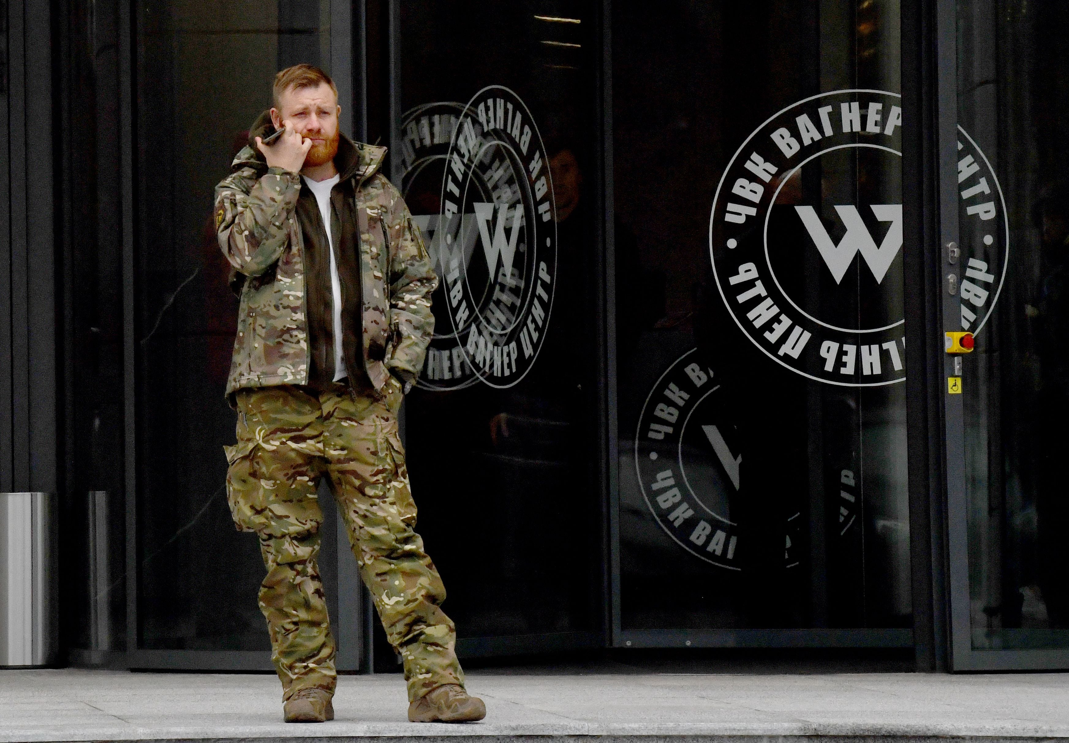 <p>A man wearing military camouflage stands at entrance of the PMC Wagner Centre in Saint Petersburg</p>