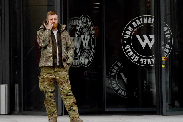 <p>A man wearing military camouflage stands at entrance of the PMC Wagner Centre in Saint Petersburg</p>