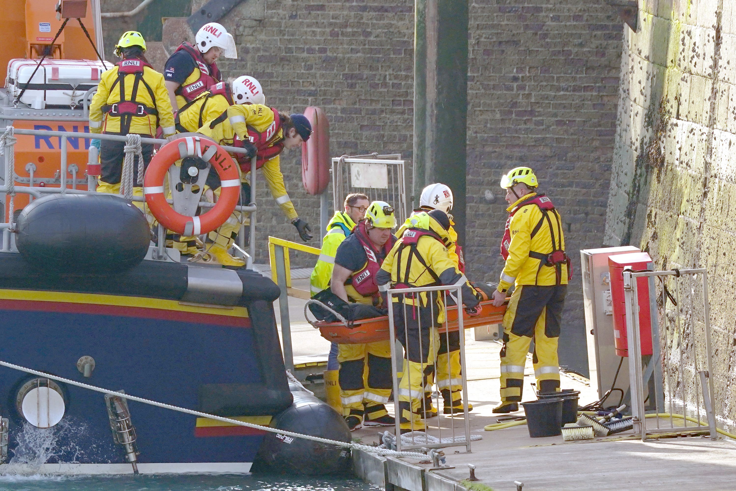 Members of the RNLI remove a stretcher and body bag from the Dover lifeboat after it returned to the port following a large search and rescue operation in the Channel (PA)