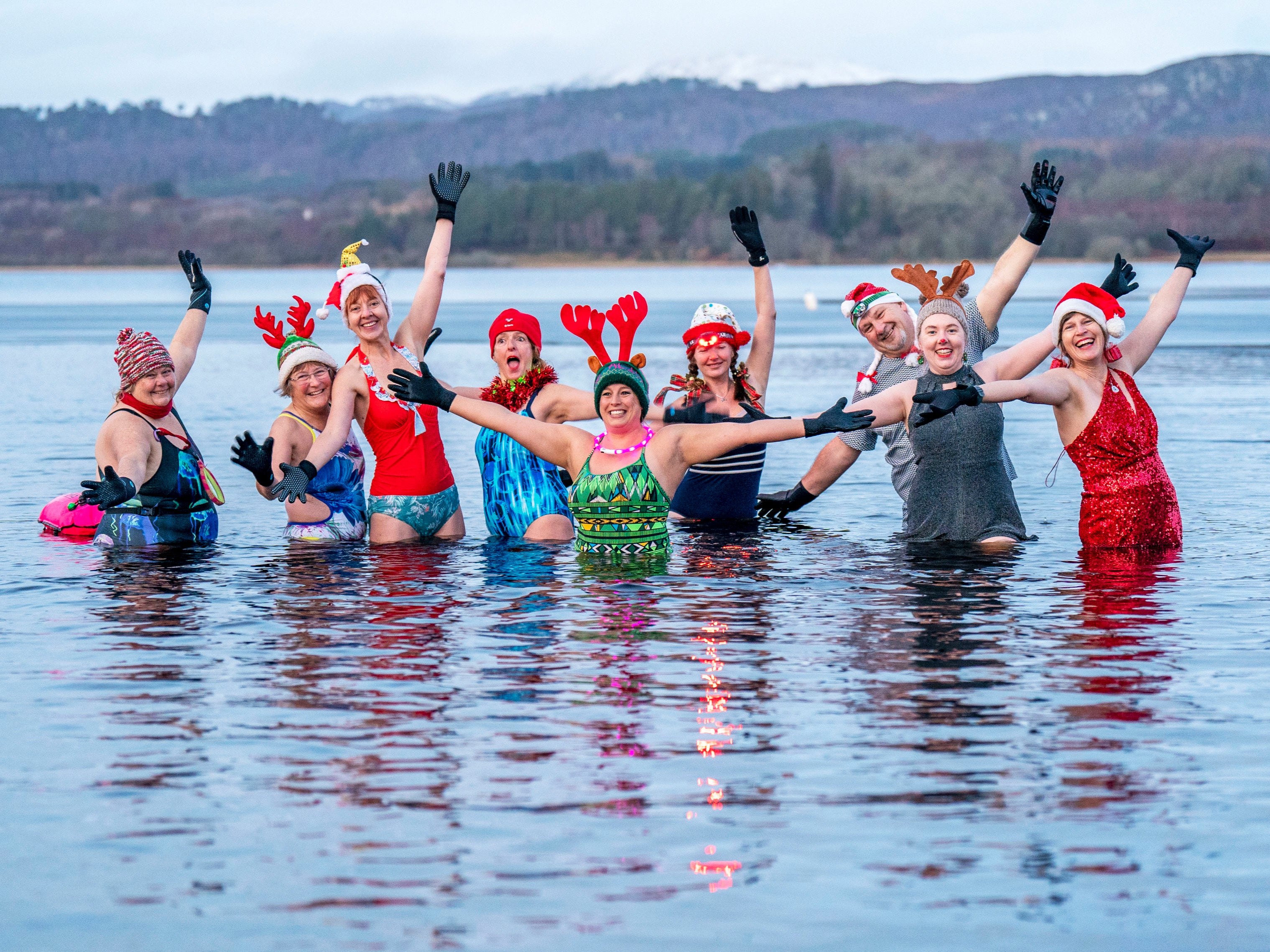 Members of the Loch Insh Dippers wild swim group take part in a Christmas-themed swim in Loch Insh in the Cairngorms National Park near Aviemore, Scotland