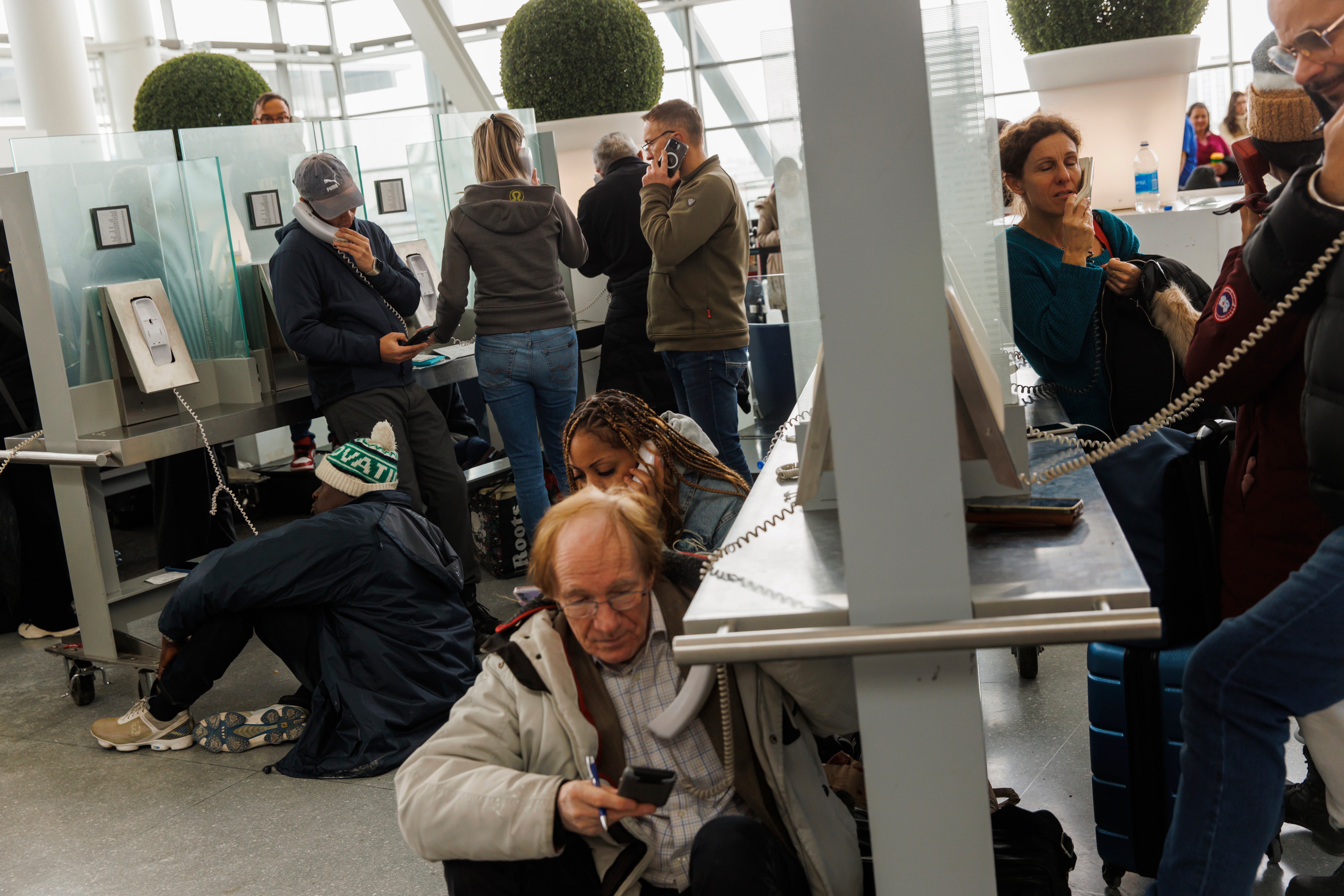 Travellers wait on hold as they try and speak with their respective airlines at Toronto Pearson International Airport, as a major winter storm disrupts flights in and out of the airport, in Toronto, Saturday, Dec. 24, 2022