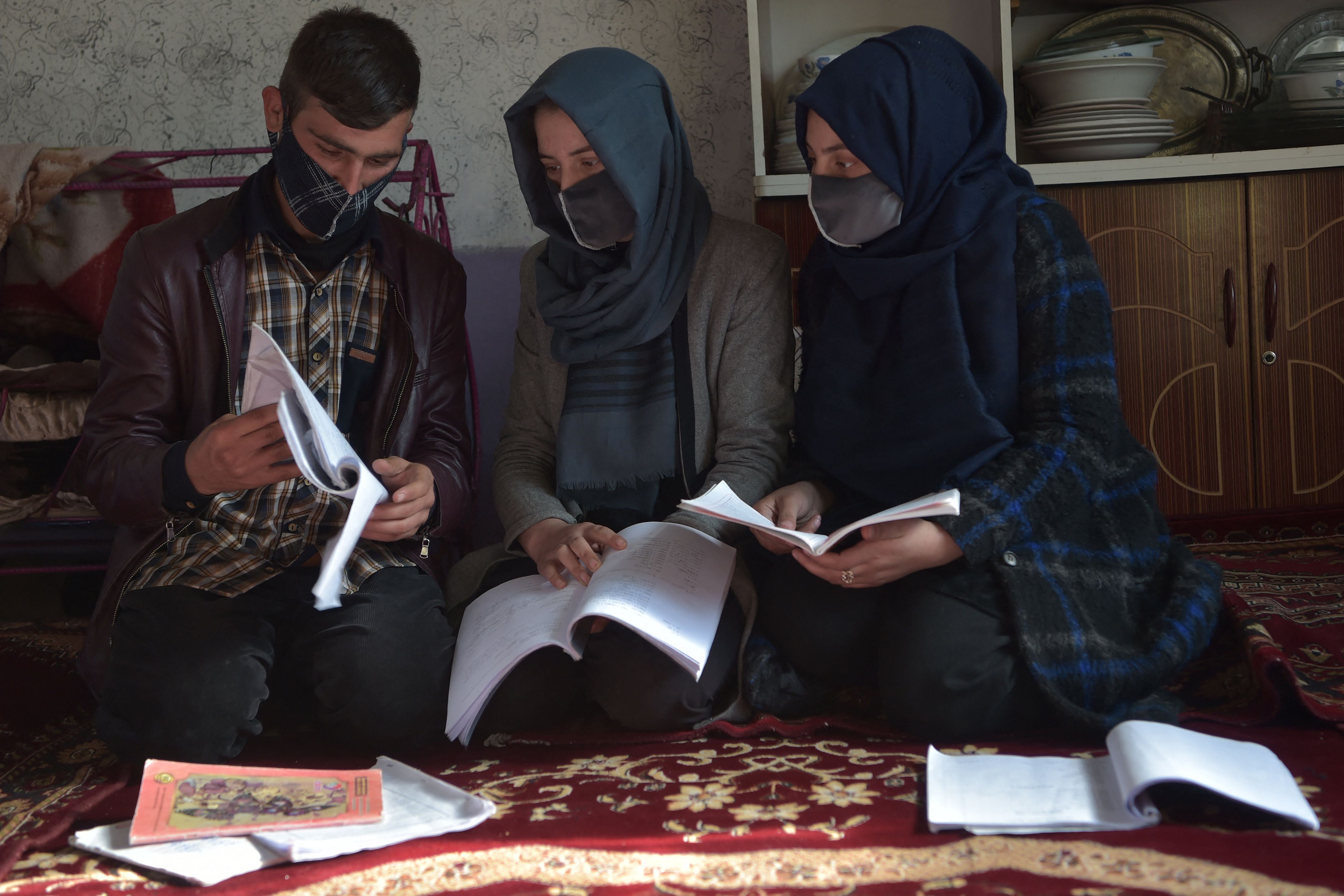 Marwa (centre) with her brother Hamid (left) at home in Kabul. He will go to university because she is now banned by the Taliban.