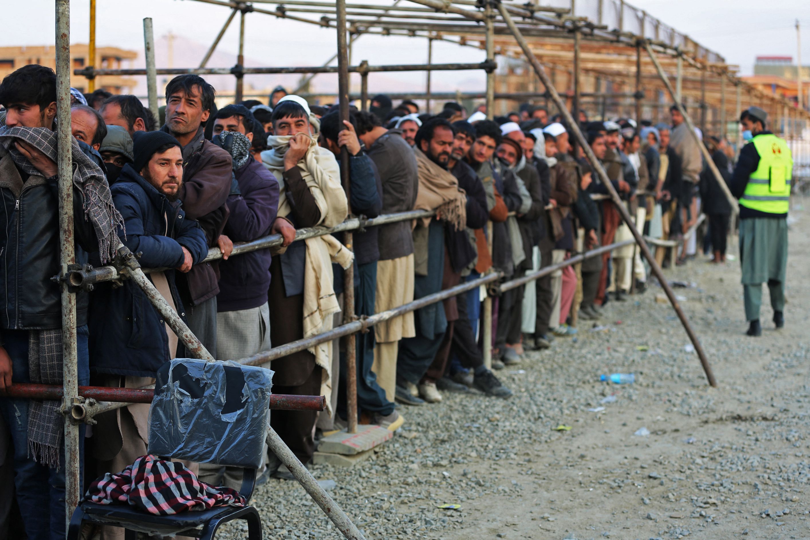 Afghan men stand in queues to receive food aid in Kabul on 25 December