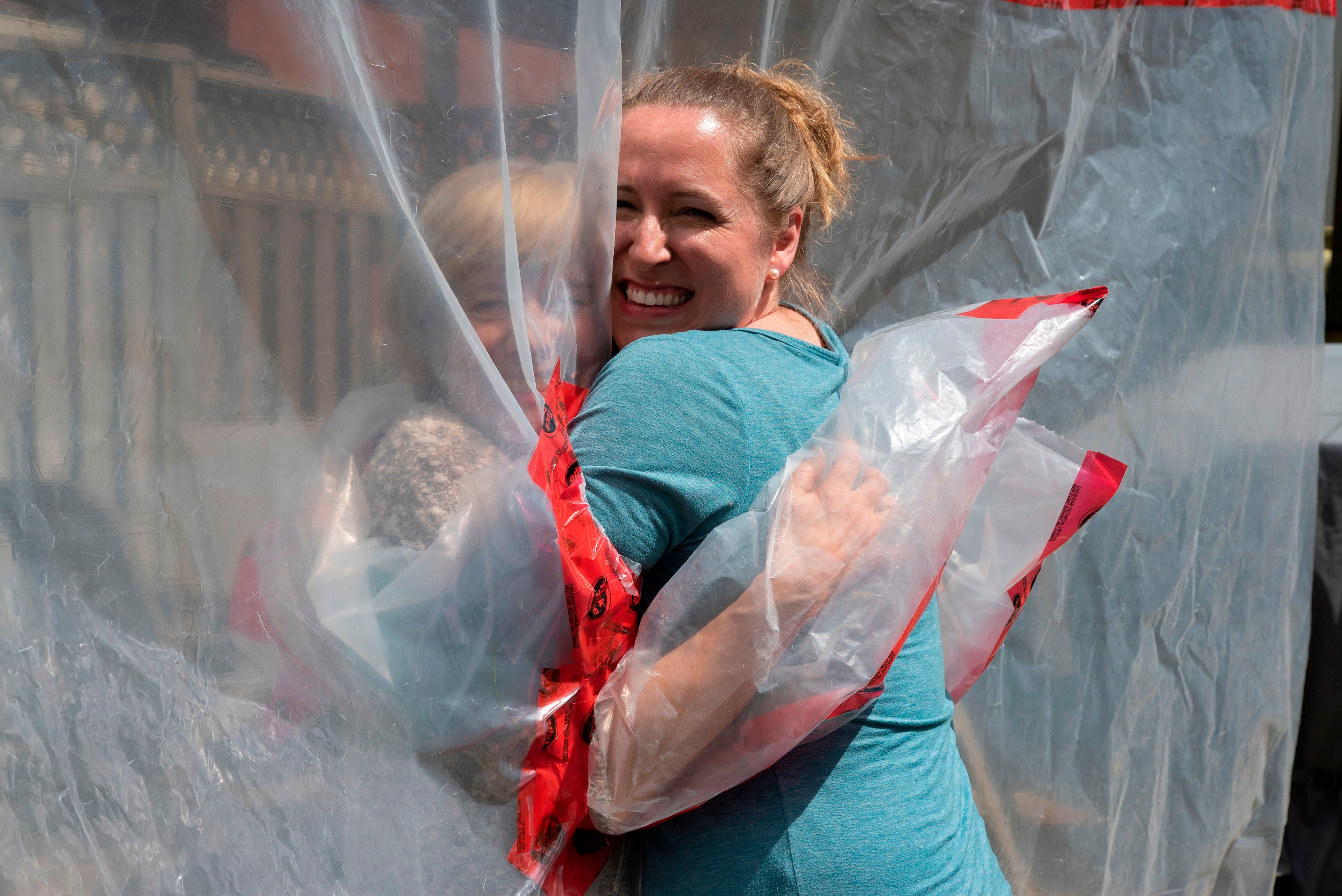 <p>Carolyn Ellis (right) hugs her mother Susan Watts on 16 May 2020 using the ‘hug glove’ that Carolyn and her husband Andrew Ellis created as a Mother’s Day gift</p>