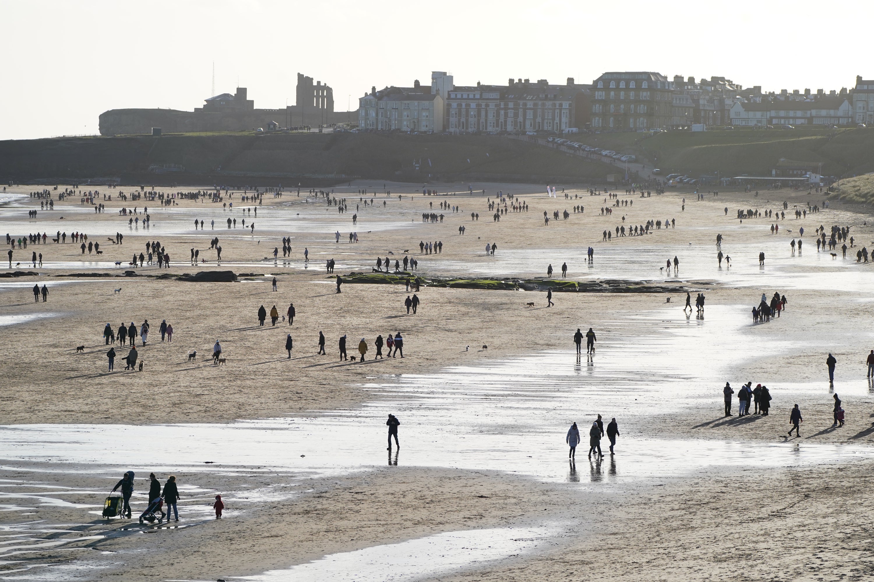People walk along Tynemouth Longsands Beach in Tynemouth in the North East of England