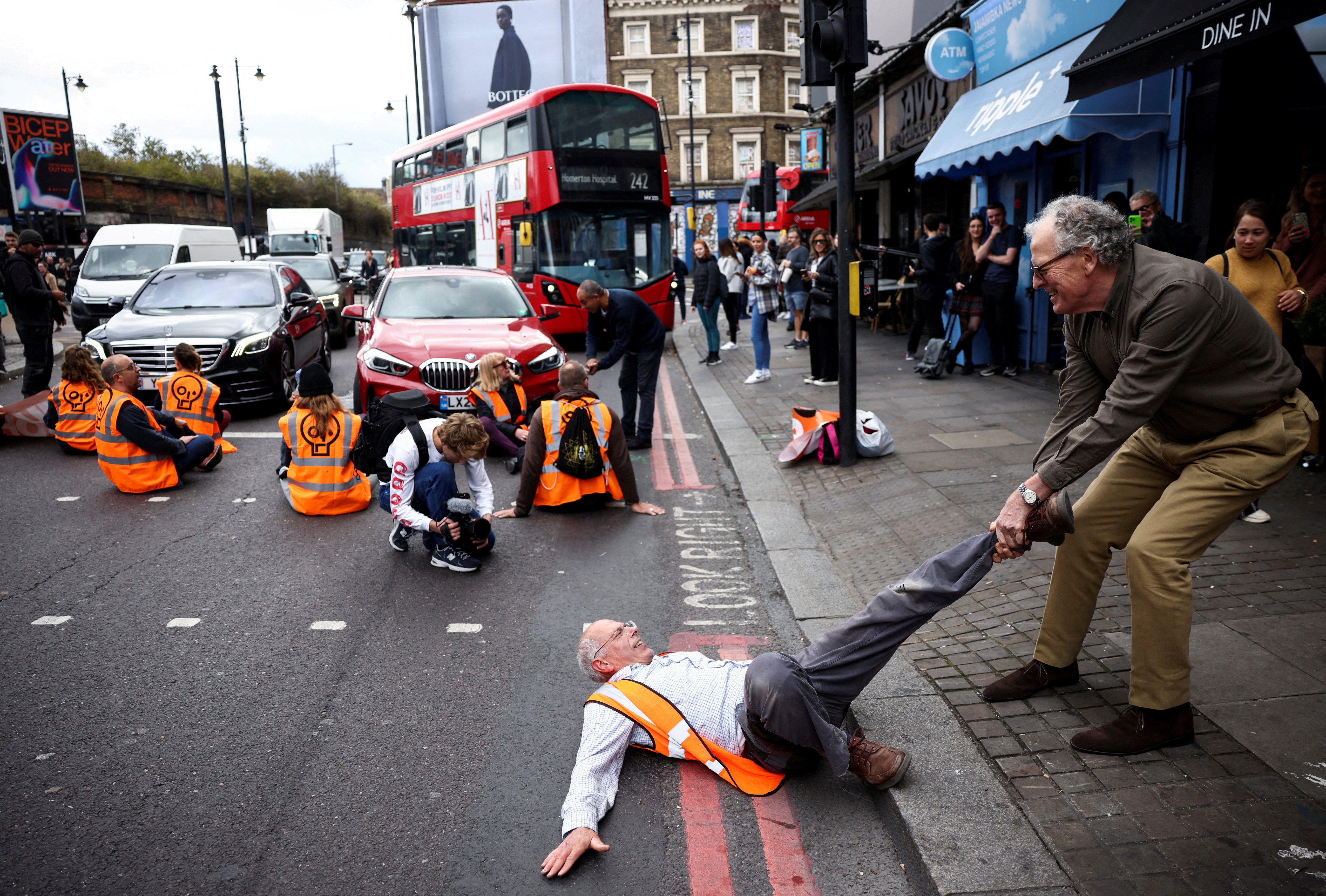 A member of the public drags an activist who is blocking the road during a Just Stop Oil protest, in London