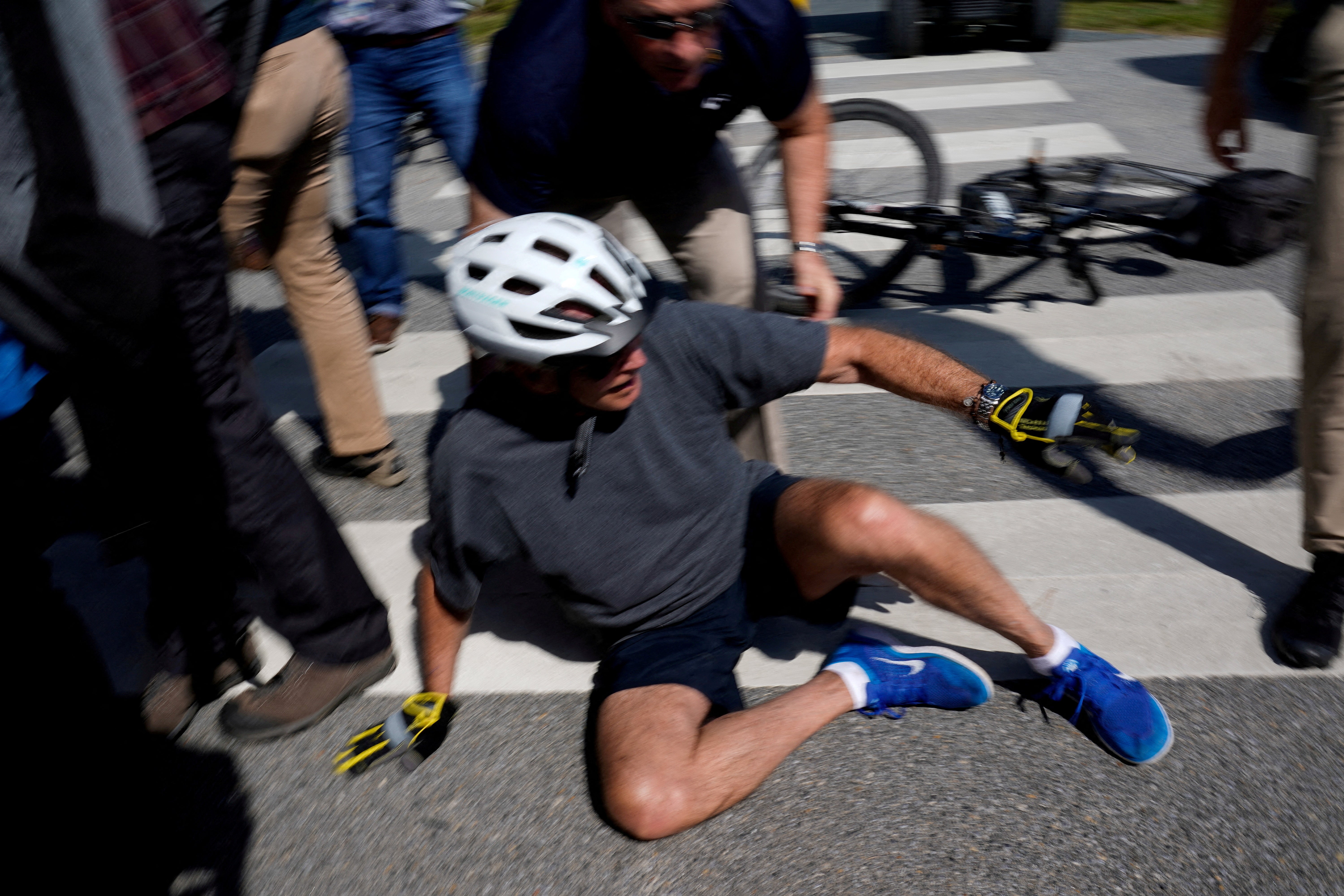 Joe Biden falls to the ground after riding up to members of the public during a bike ride in Rehoboth Beach