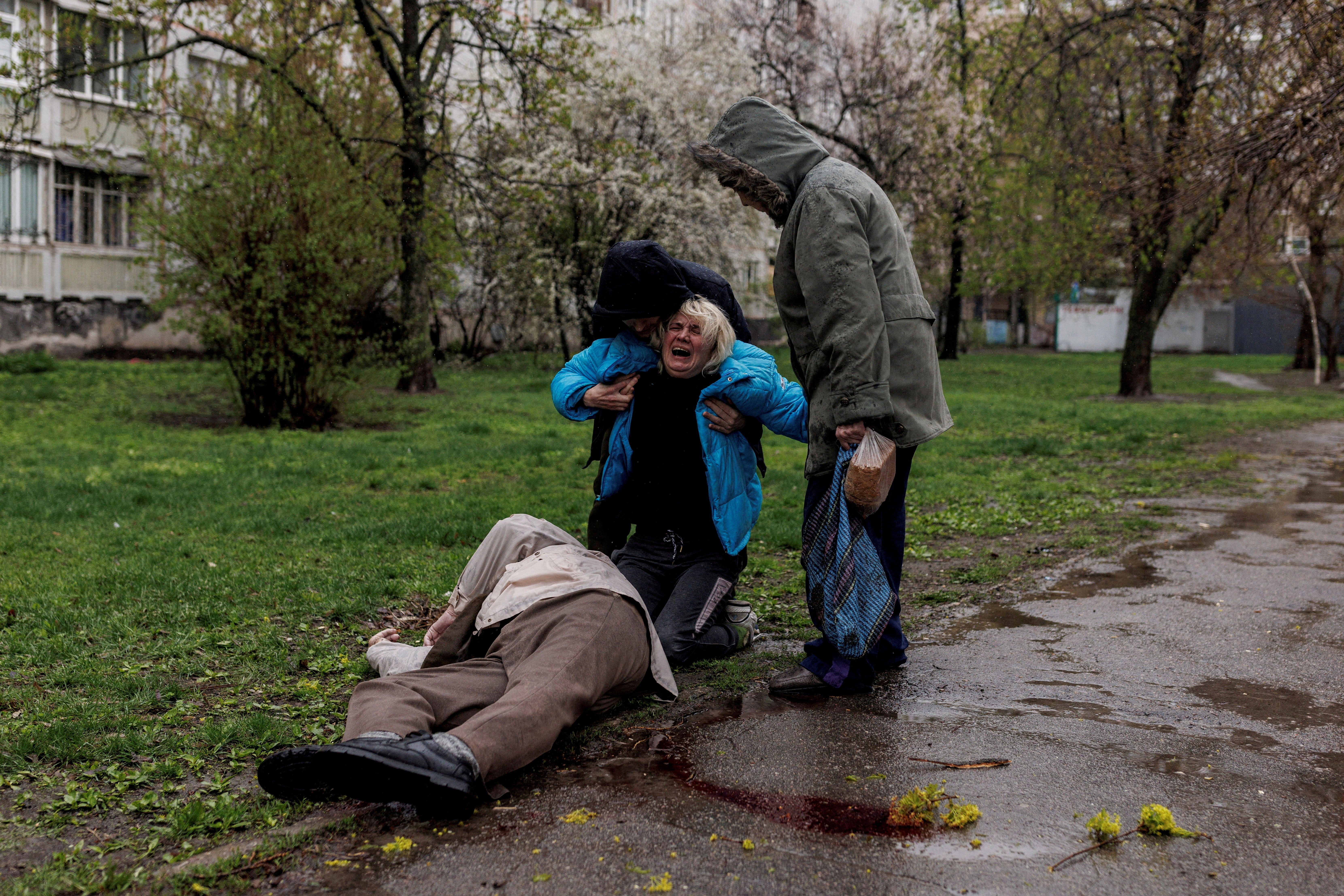 Yana Bachek is consoled by her partner Yevgeniy Vlasenko and her mother Lyubov Gubareva, as she mourns over the body of her father Victor Gubarev, 79, killed by shelling during Russia's invasion of Ukraine