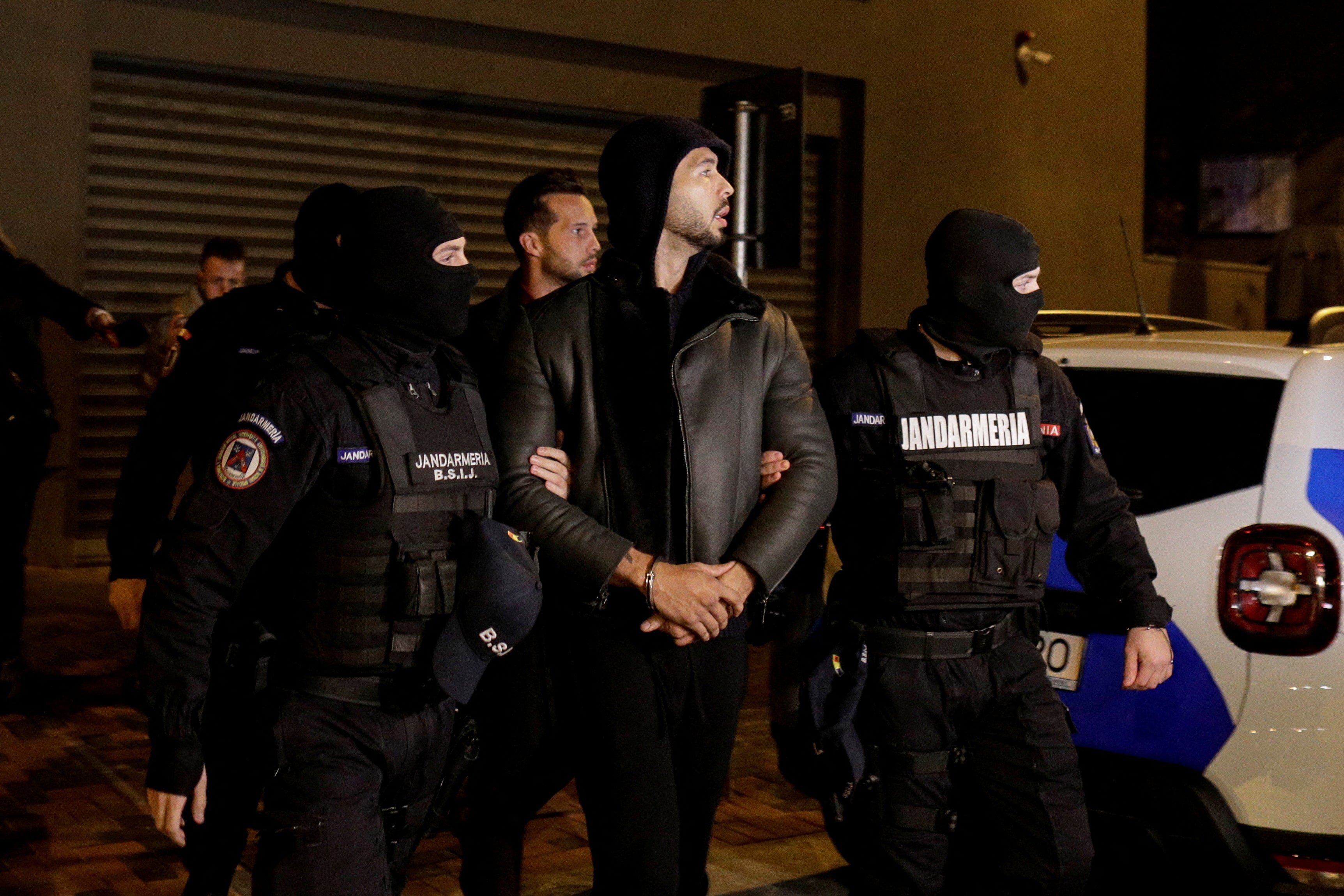 Andrew Tate and Tristan Tate are escorted by police officers outside the headquarters of the Directorate for Investigating Organized Crime and Terrorism in Bucharest