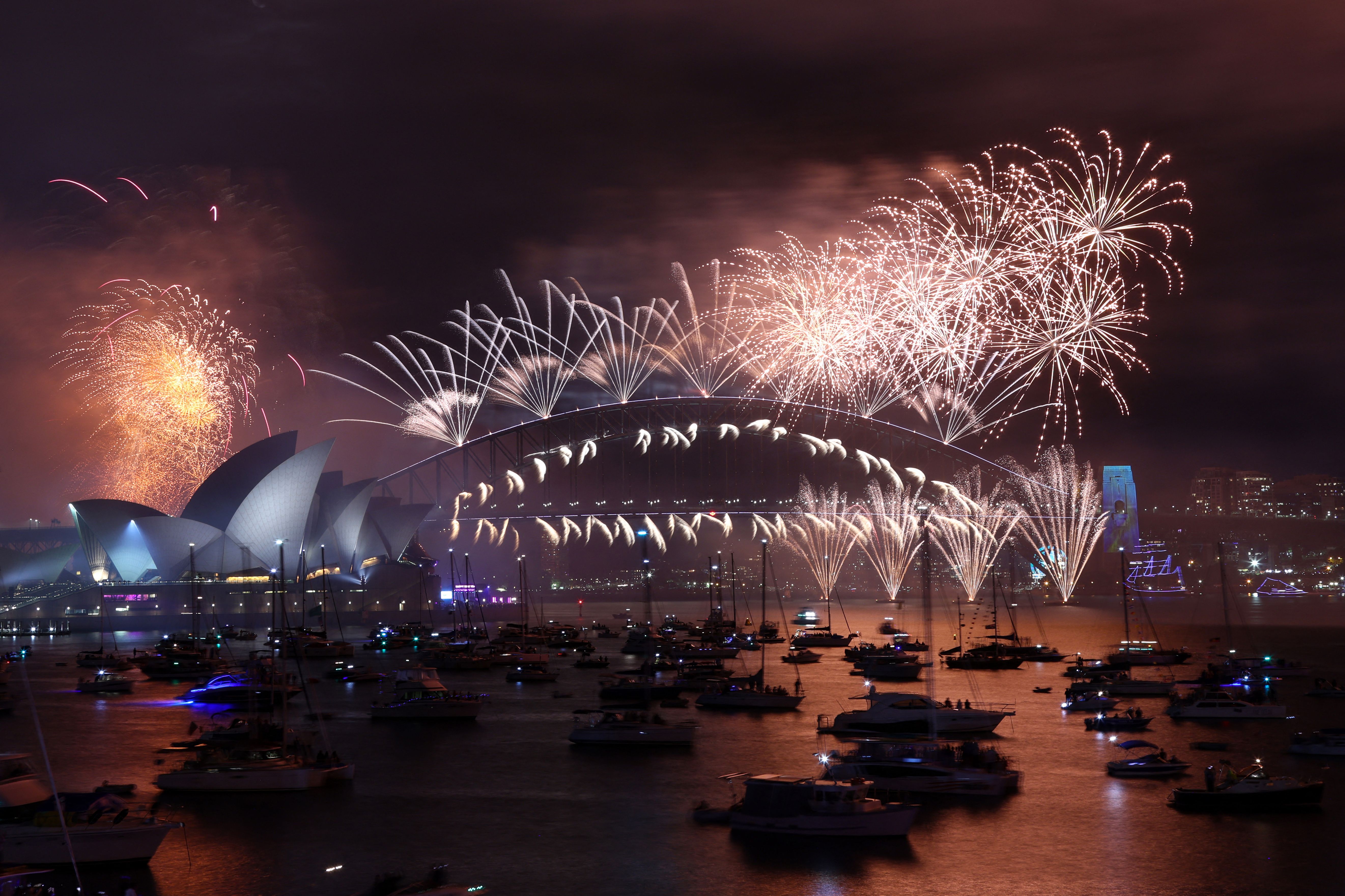 New Year's Eve fireworks light up the sky over the Sydney Opera House (L) and Harbour Bridge during the fireworks display in Sydney on January 1, 2023.