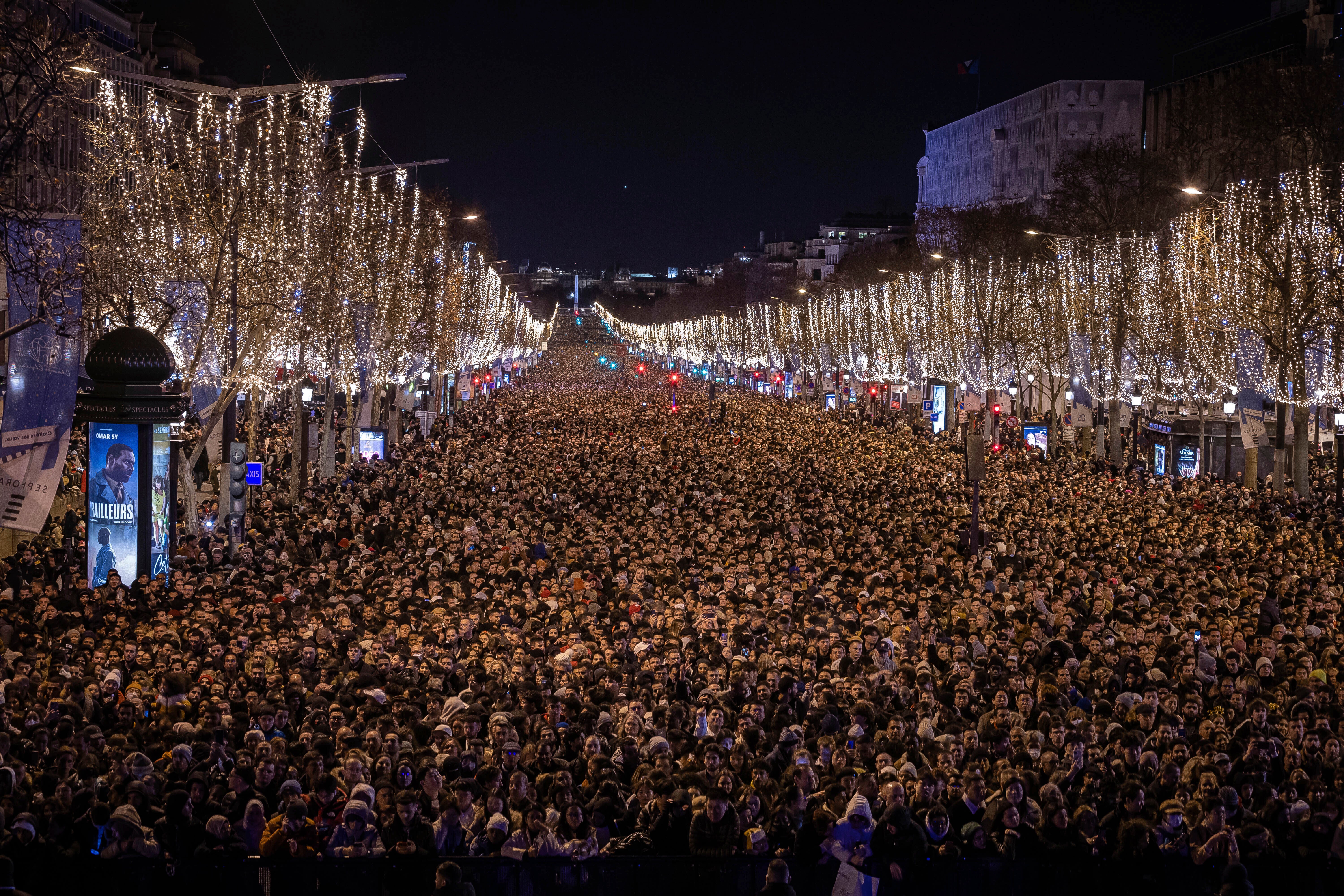 Revellers watch a sound and light show projected on the Arc de Triomphe as they celebrate the New Year on the Champs Elysees in Paris