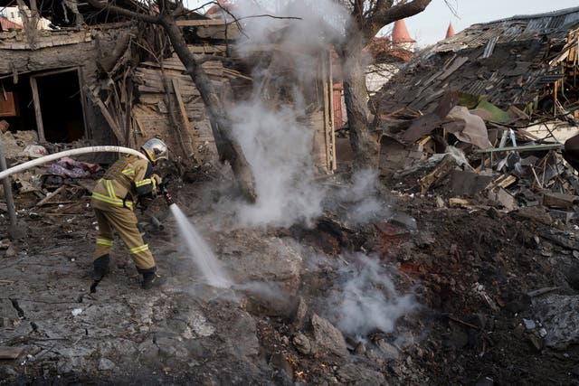 Firefighters extinguish a fire next to houses destroyed during a Russian attack on Kyiv (Roman Hrytsyna/AP)