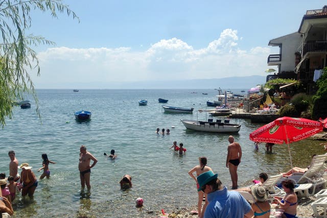 <p>Holidaymakers at Ohrid in North Macedonia with the hills of Albania in the distance</p>