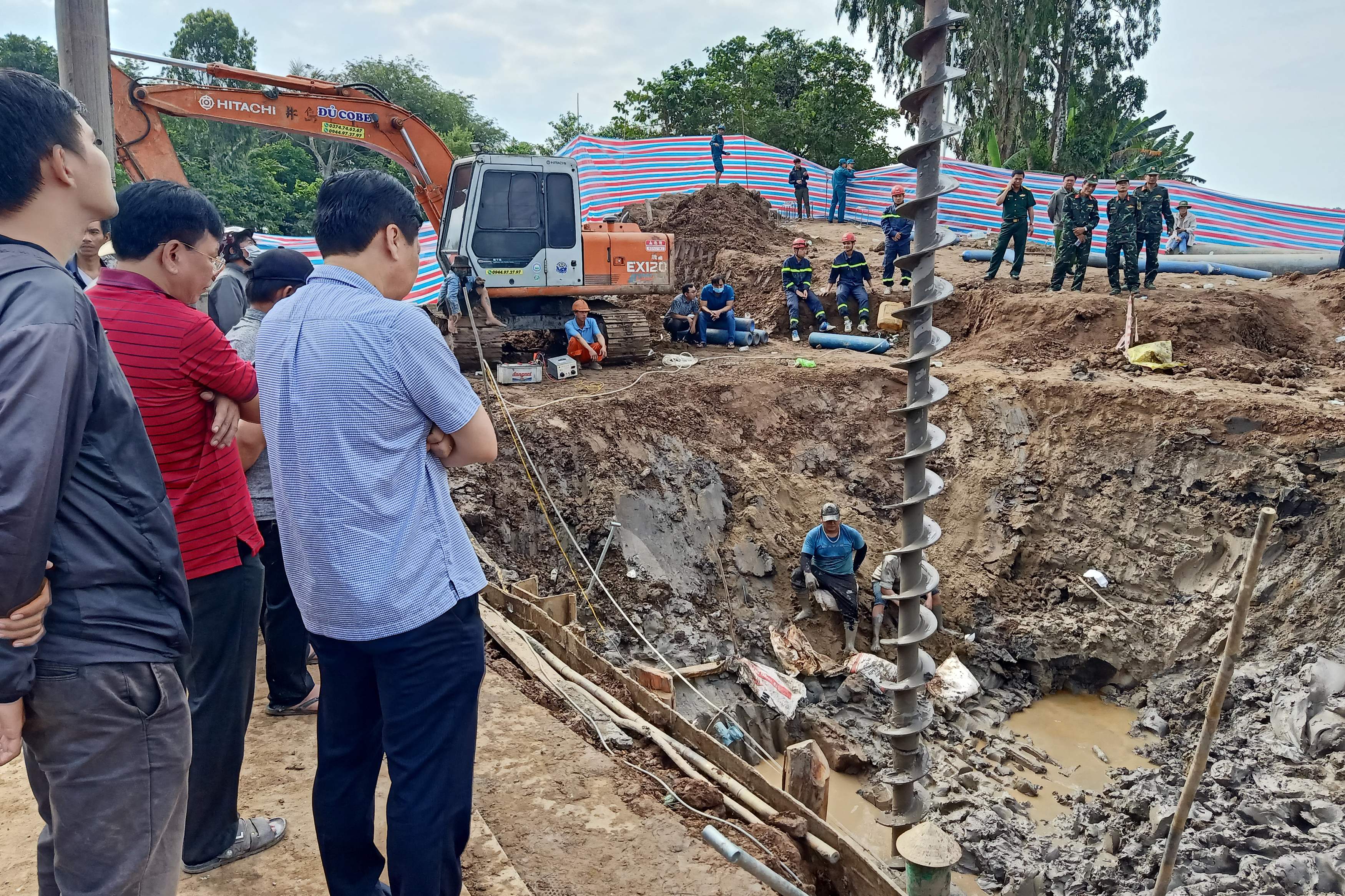 Rescuers look down into the site of where a 10-year-old boy is thought to be trapped in a 35-metre deep shaft