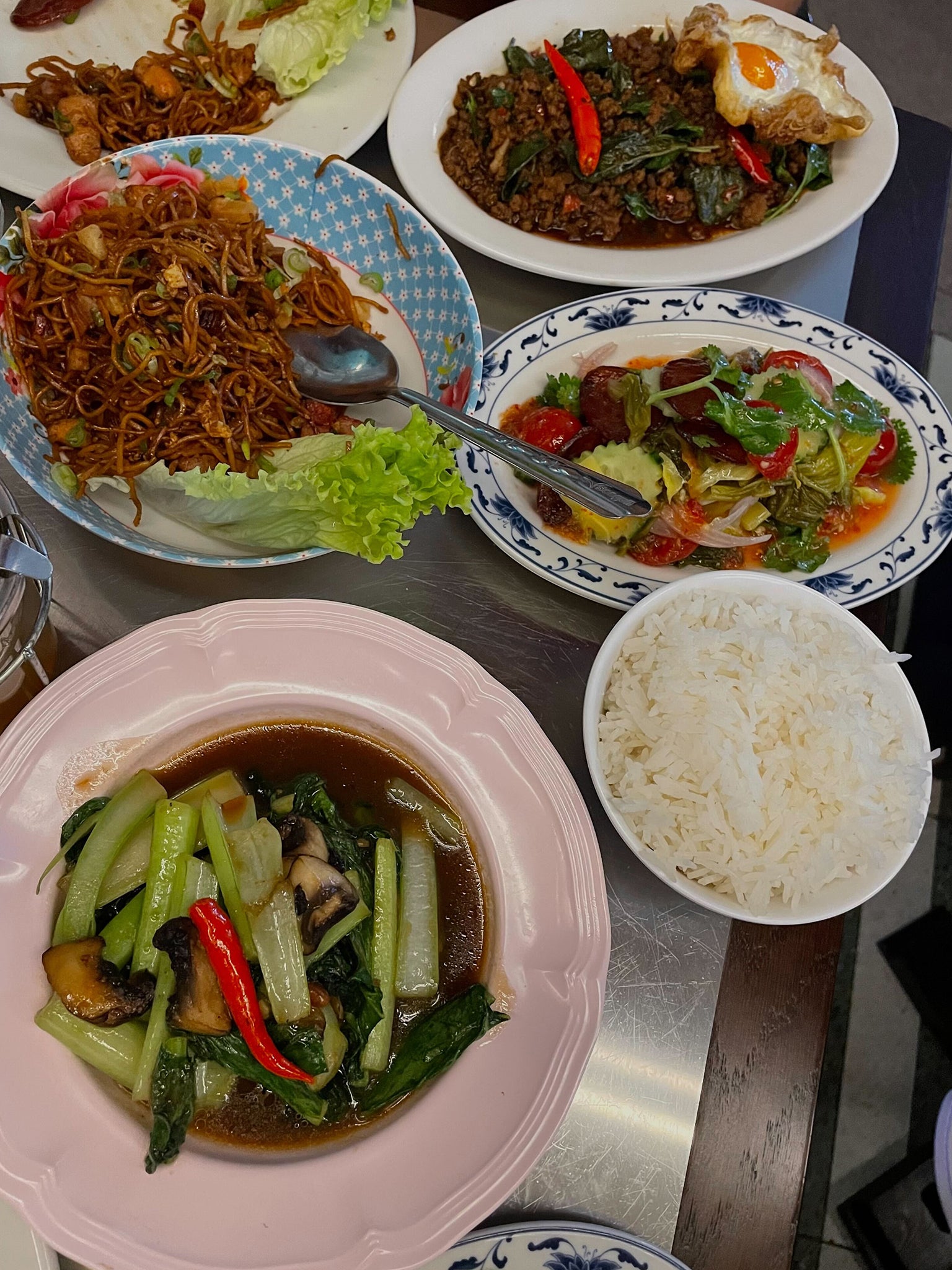 Clockwise from top right: pad krapow, pickled mustard greens and Chinese sausage, steamed vegetables in soy bean sauce, and chicken noodles in red roast pork sauce