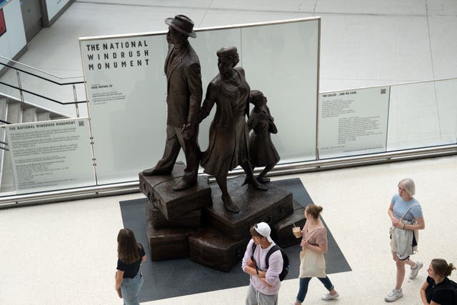 <p>People view the  statue dedicated to the Windrush generation at Waterloo station unveiled in June. Today, voices from across the UK are speaking out about Windrush 75 </p>