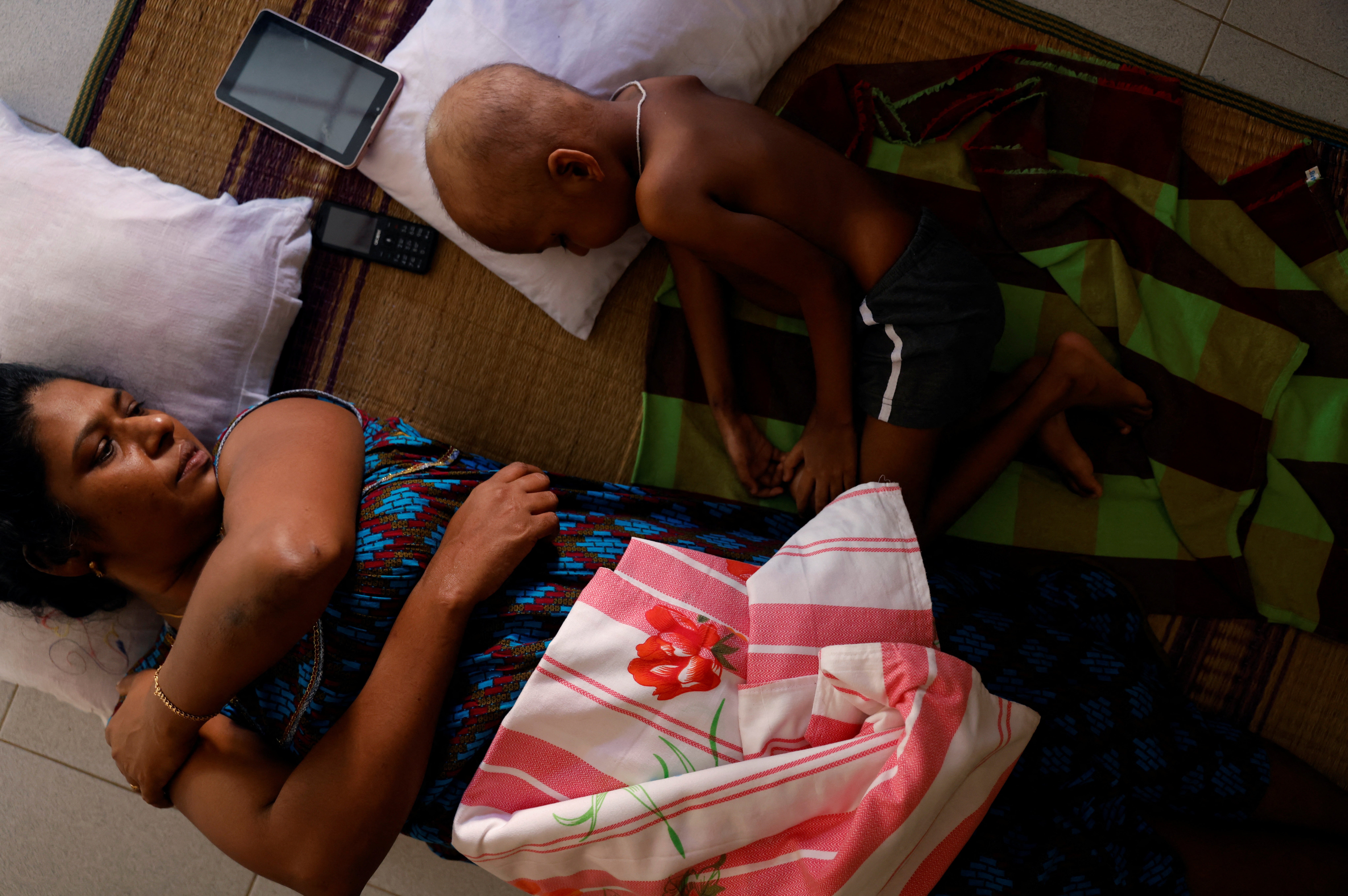 Ratnasingham Rajini watches her grandson S Saksan, 5, who has leukaemia, while he sleeps in a corridor of a cancer care transit home