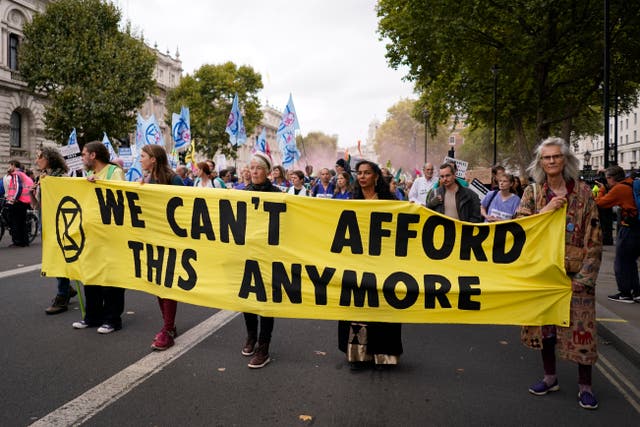 <p>Extinction Rebellion protesters hold up a banner as they march along Whitehall near Downing Street in London in October 2022 </p>