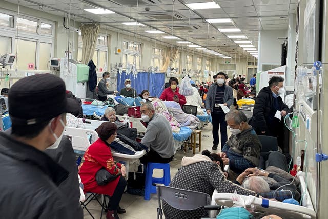 <p>Patients lie on beds in the emergency department of a hospital during a Covid surge across China</p>