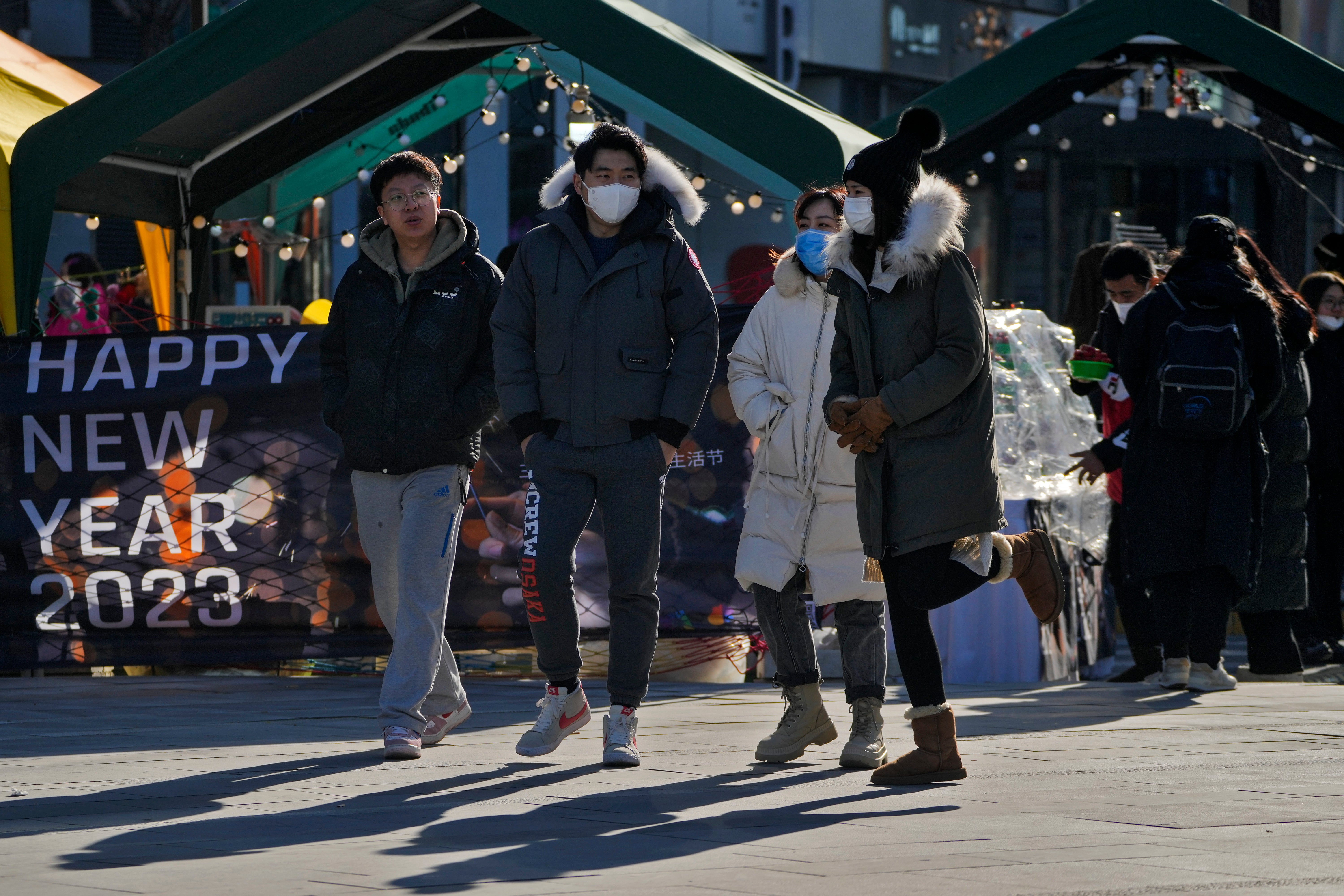 People wearing face masks walk through a bazaar outside a commercial office building in Beijing