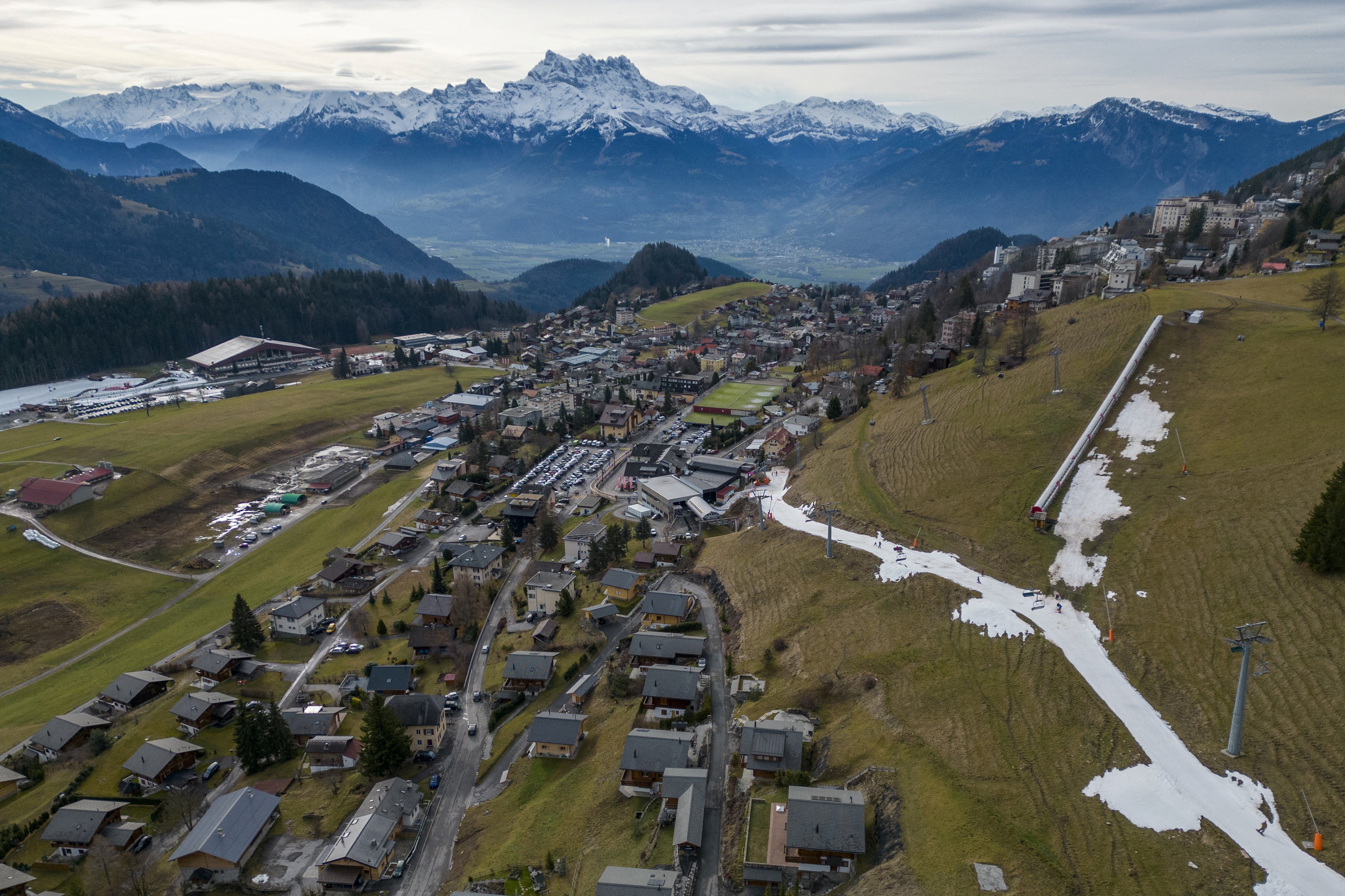 Skiers pass on a small layer of artificial snow amid warmer-than-usual winter temperatures in the Alps in Leysin, Switzerland on 4th January