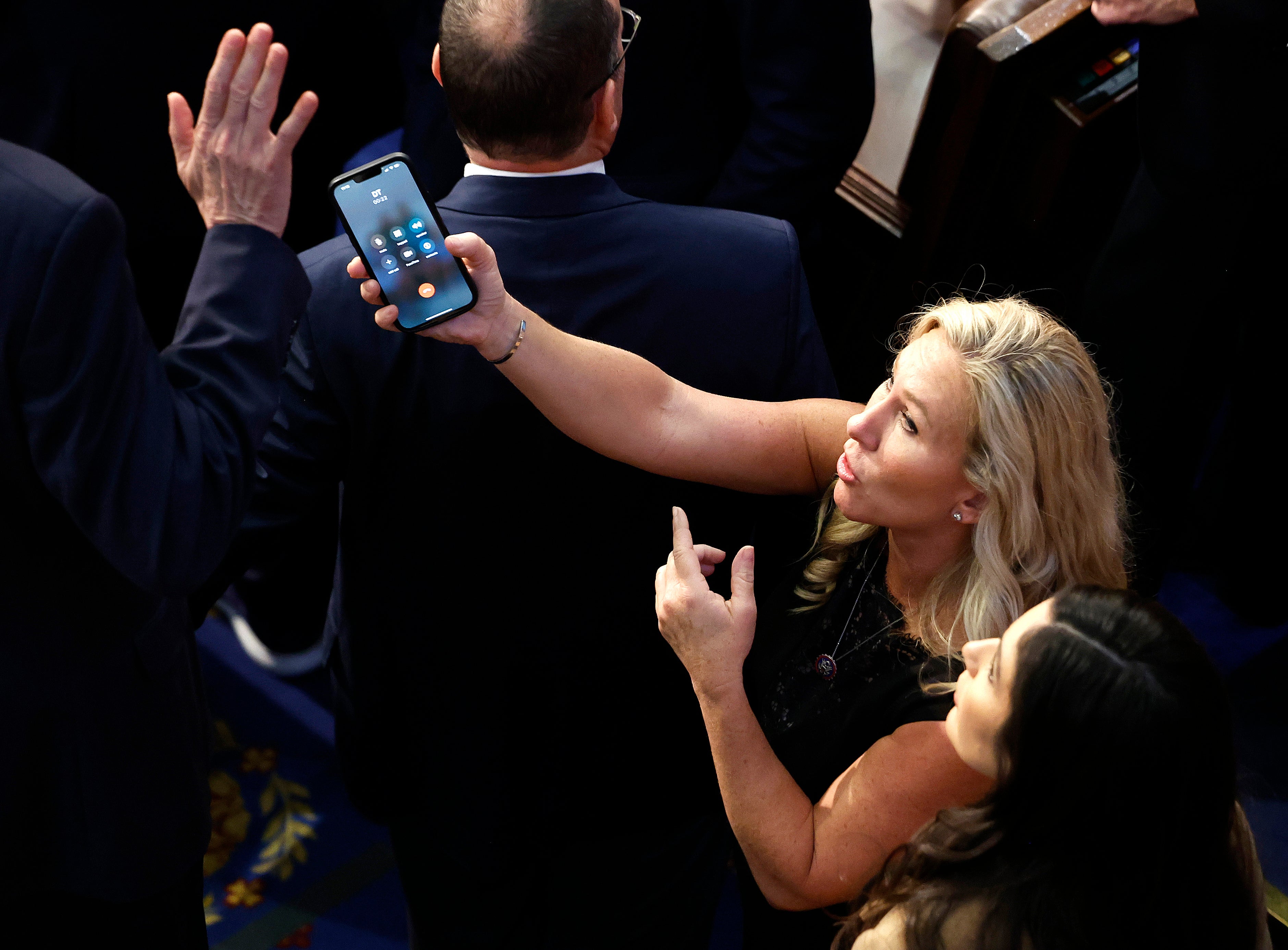 US representative-elect Marjorie Taylor Greene offers a phone to Matt Rosendale in the House Chamber during the fourth day of voting for Speaker of the House at the US Capitol Building on 6 January 2023 in Washington, DC