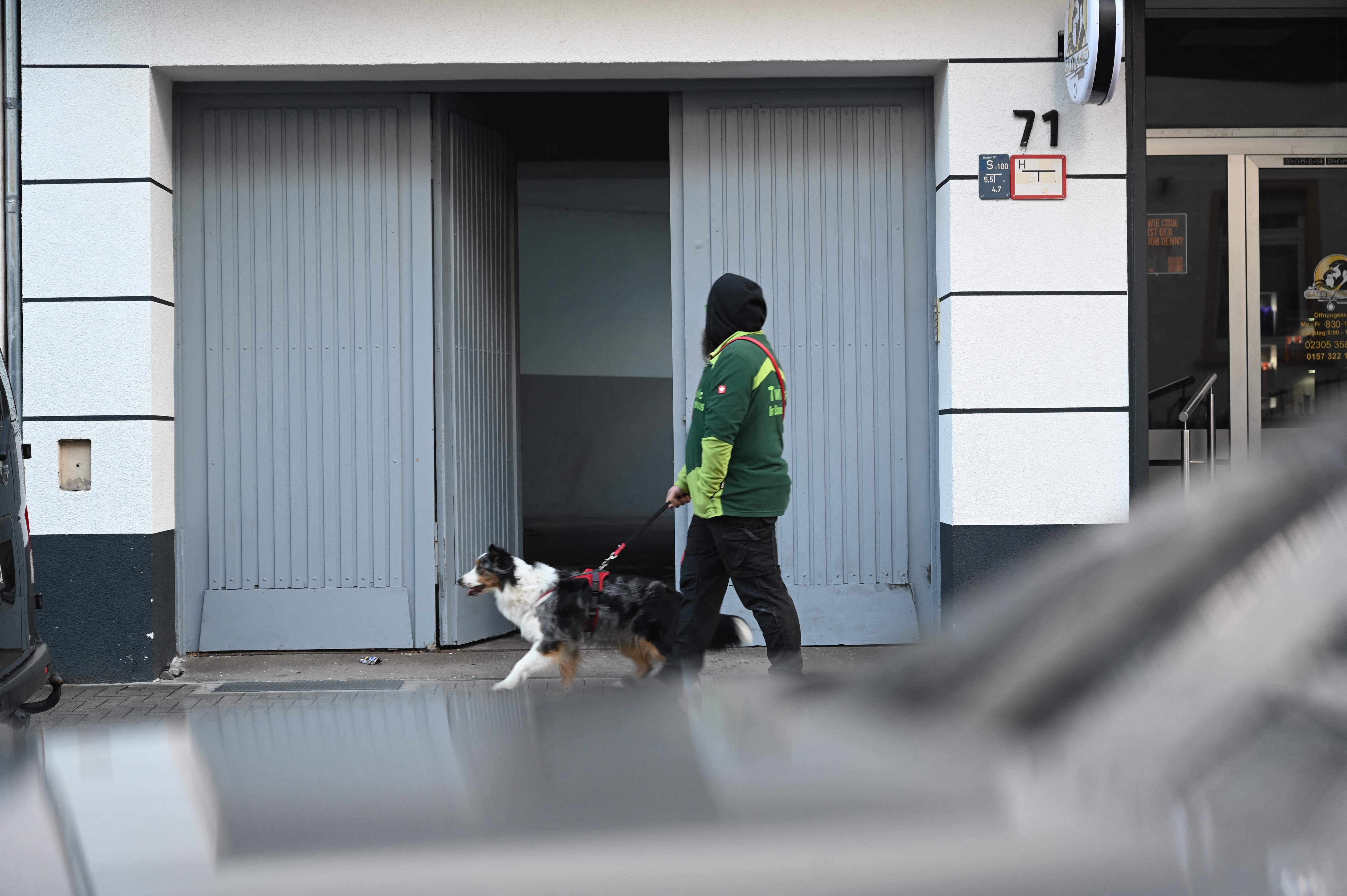A dog walker passes the entrance to a house in Castrop-Rauxel where police arrested the suspect