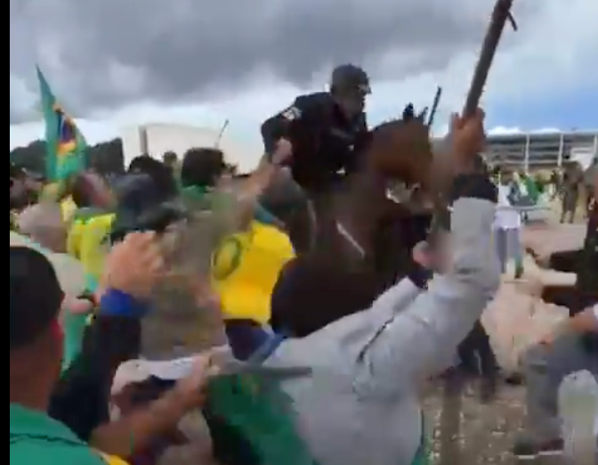 A mounted police officer is beaten and pulled from his horse by a mob of pro-Bolsonaro rioters in Brazil on Sunday