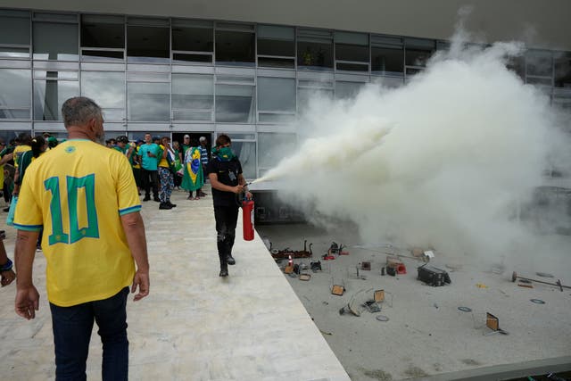 A protesting supporter of Brazil’s former president Jair Bolsonaro launches a fire extinguisher after protesters stormed Planalto Palace in Brasilia, Brazil (Eraldo Peres/AP)