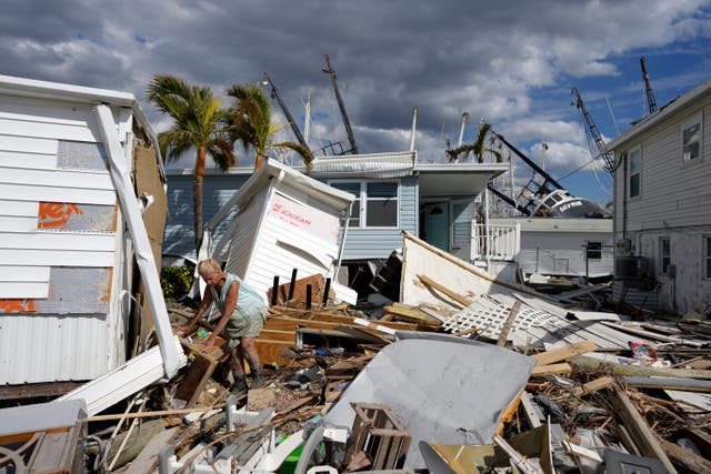 <p>Kathy Hickey, 70, carefully picks her way through debris from destroyed trailers in the mobile home park where she and her husband Bruce had a winter home on San Carlos Island in Fort Myers Beach, Florida </p>