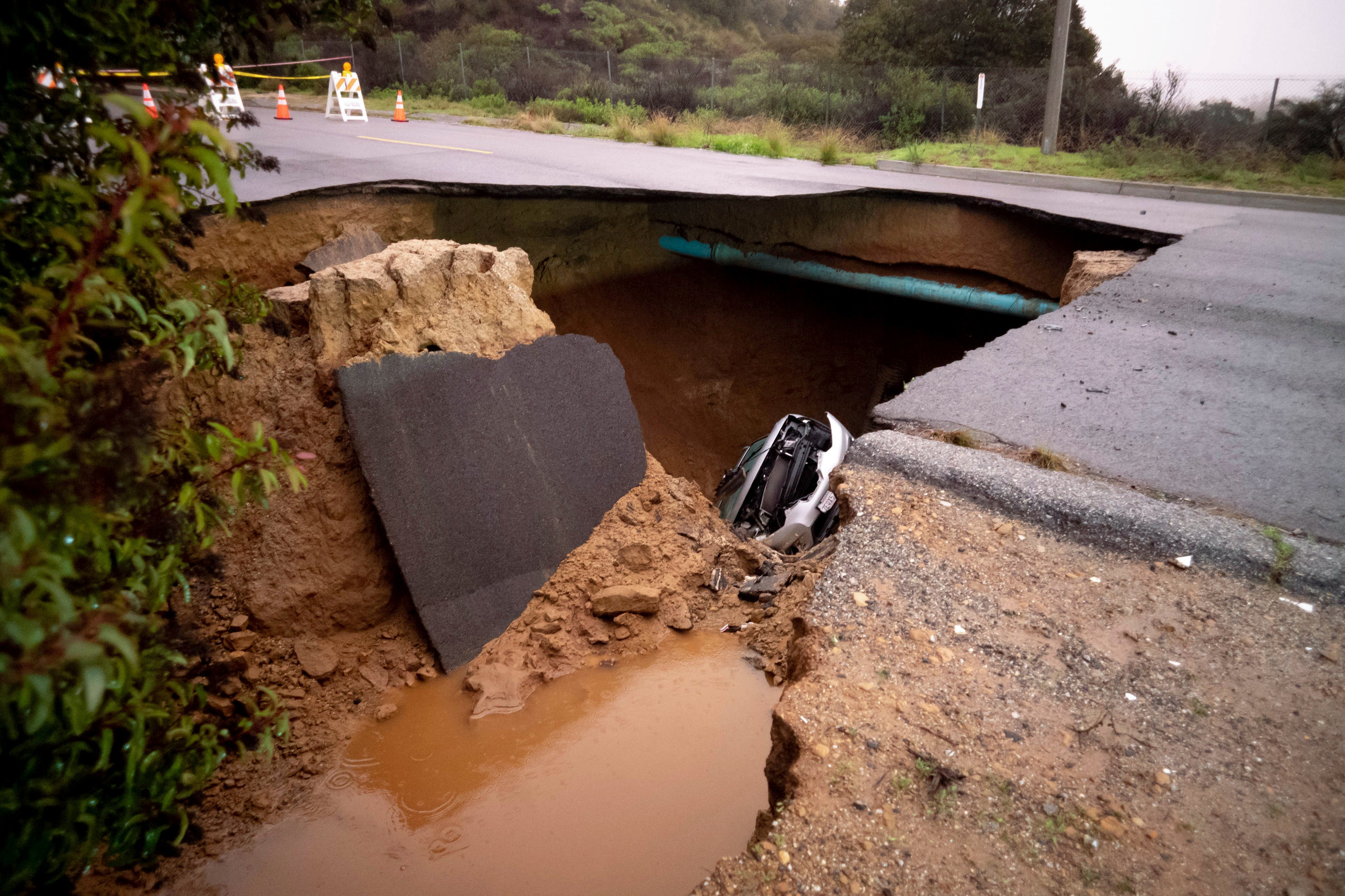 Cars remain in a large sinkhole along Iverson Road in Chatsworth, Calif., on Tuesday, Jan. 10, 2023