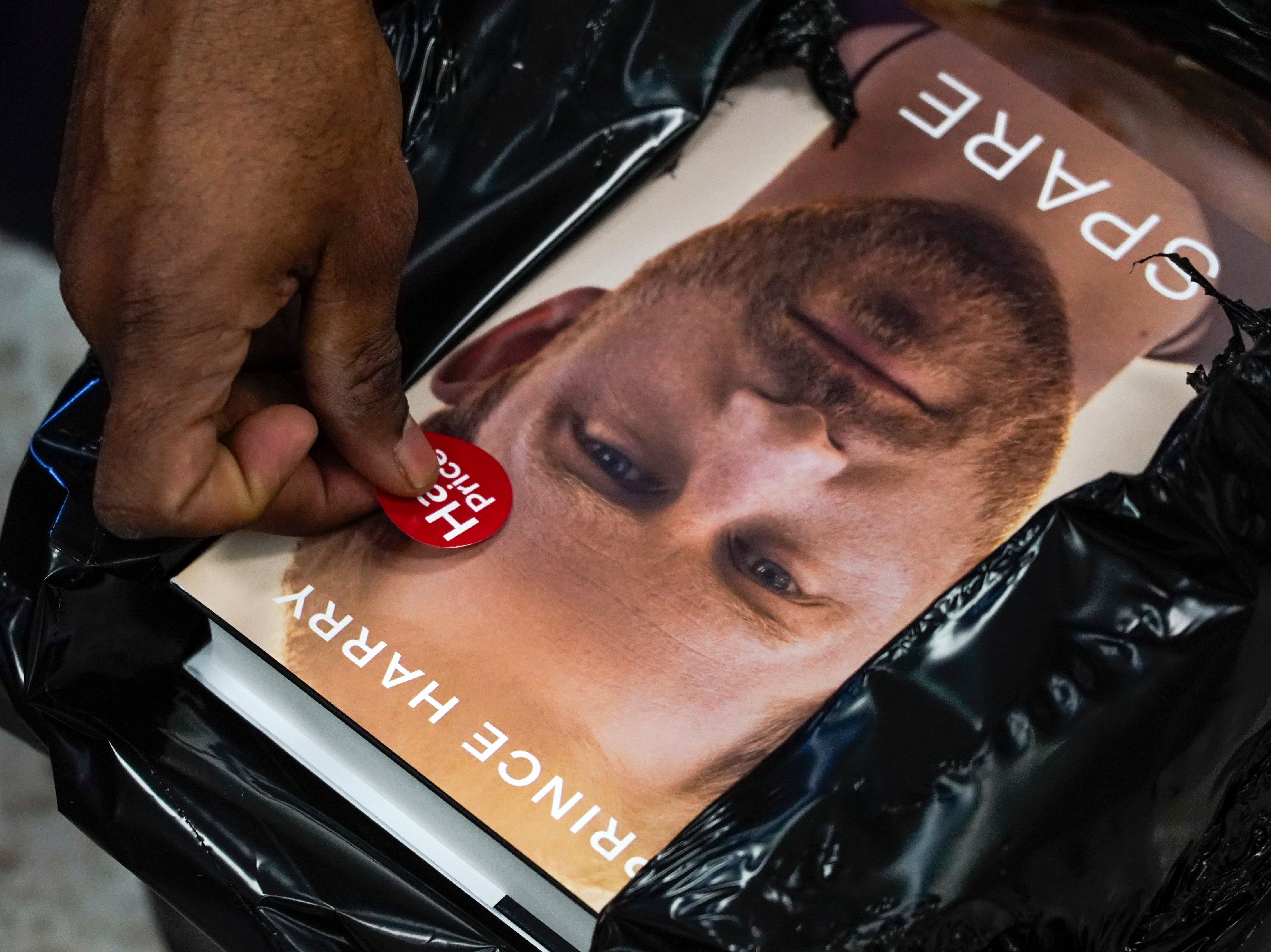 A member of staff of a book store places a half price sticker on copies of the new book by Prince Harry called “Spare” during a midnight opening in London