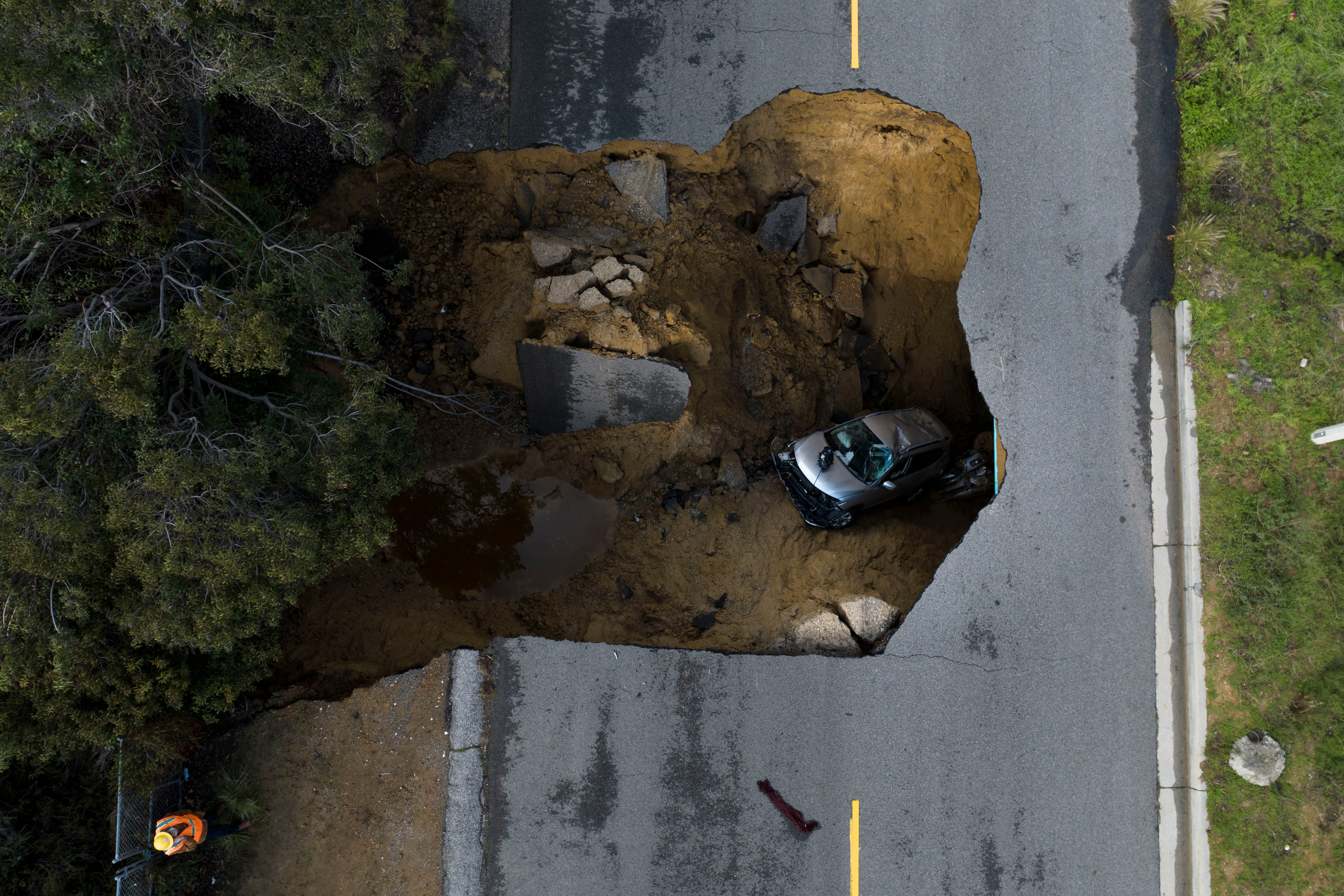 A vehicle is stuck in a sinkhole in the Chatsworth section of Los Angeles, Tuesday, Jan. 10, 2023
