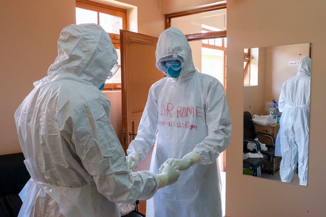 <p>Doctors wearing protective equipment pray together before they visit a patient who was in contact with an Ebola victim</p>