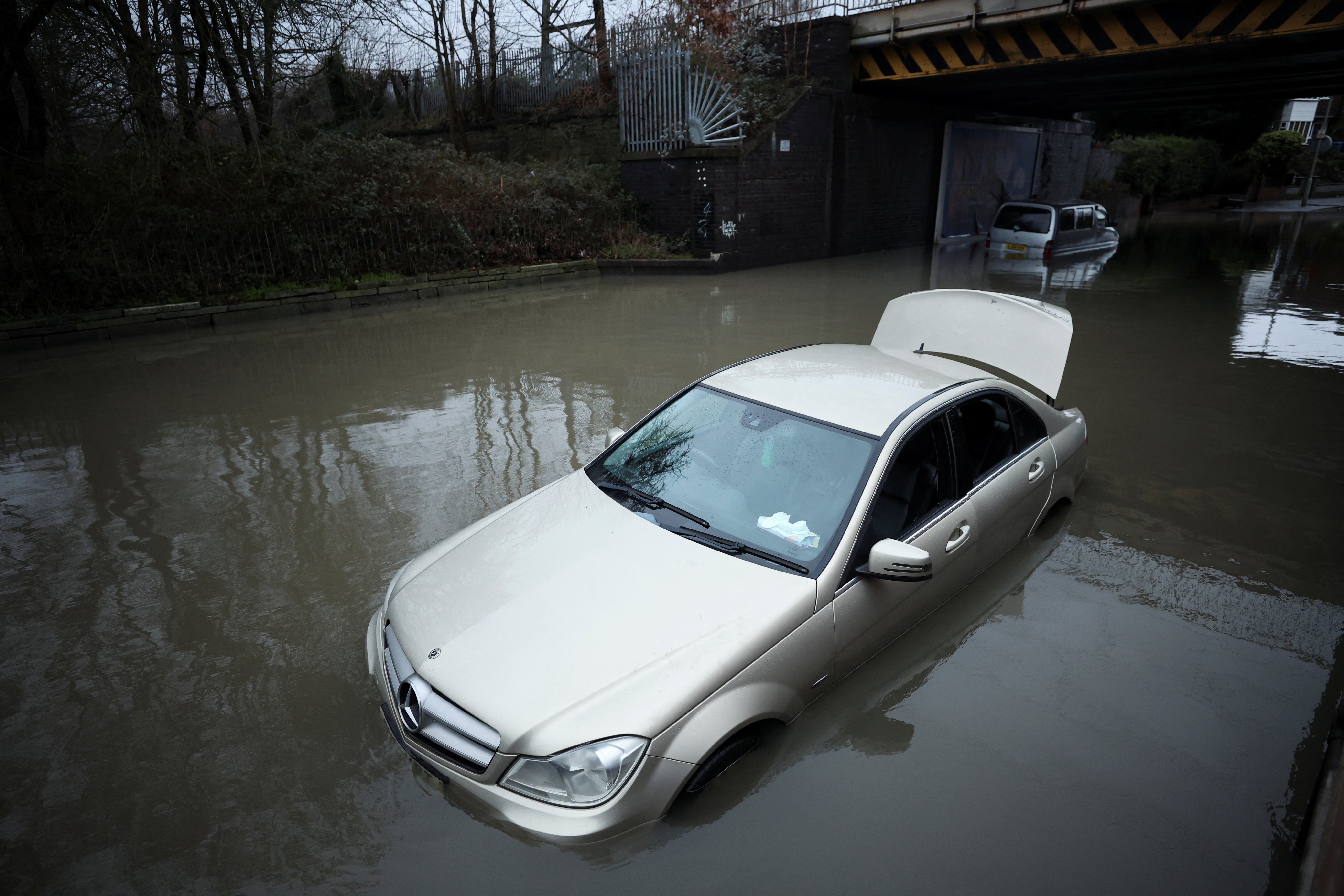 Cars are left partially submerged in water after heavy rain flooded a section of road in Stockport, Greater Manchester