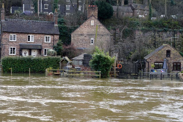 The Vic Haddock boat house (right) is flooded by the swollen River Severn, as flood defences were in place along the Wharfage at Ironbridge, Telford (PA)