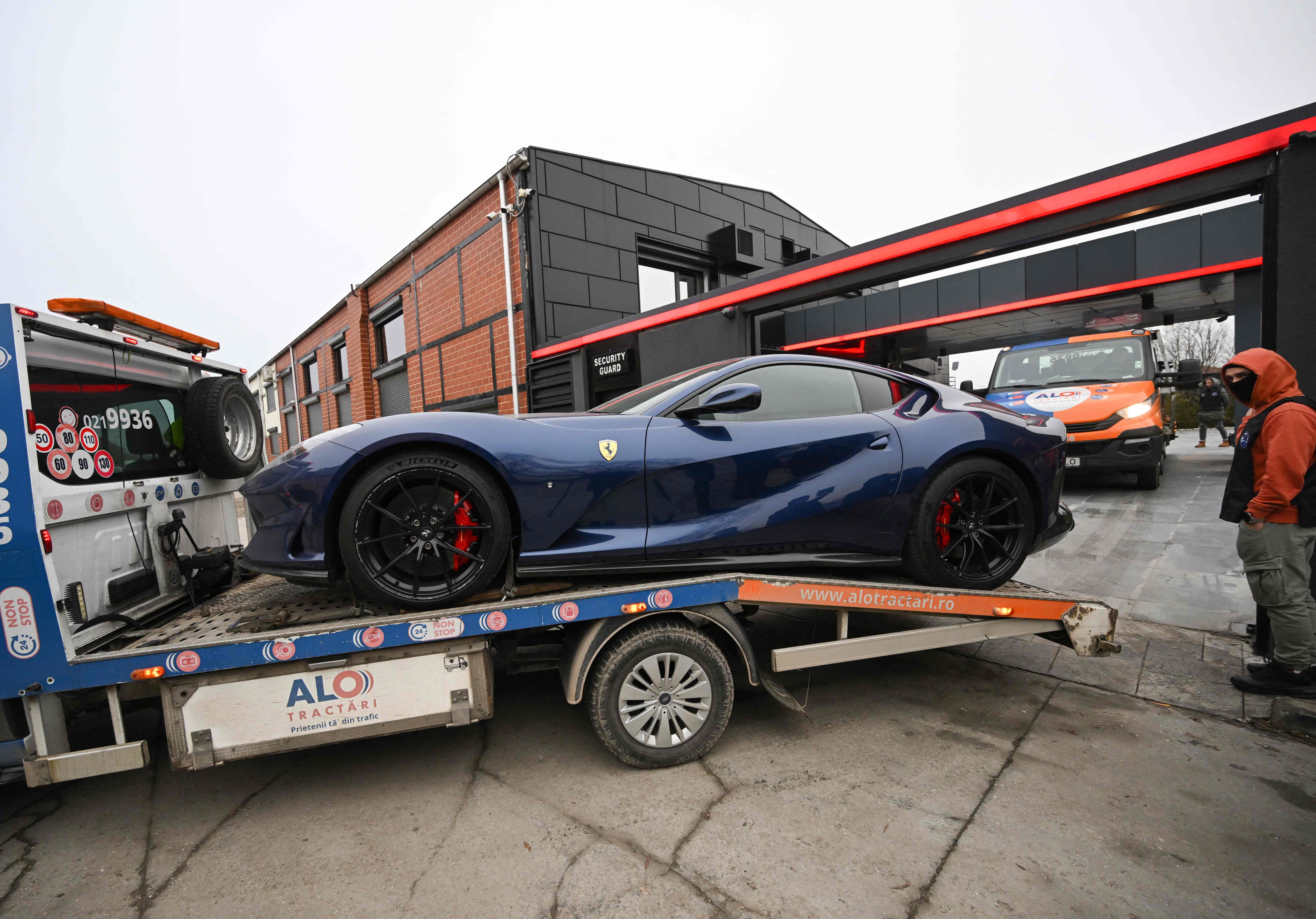 A navy blue Ferrari belonging to Andrew Tate is taken away by Romanian authorities
