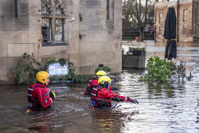 Rescue workers wade through floodwater in the centre of York after the River Ouse burst its banks (Danny Lawson/PA)