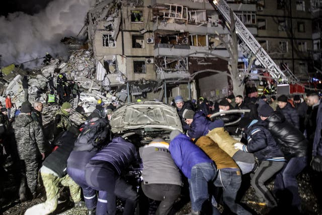 <p>Residents move a damaged vehicle as rescuers try to reach people trapped</p>