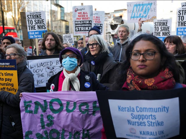 <p>NHS nurses hold signs during a strike outside University College Hospital on 20 December</p>