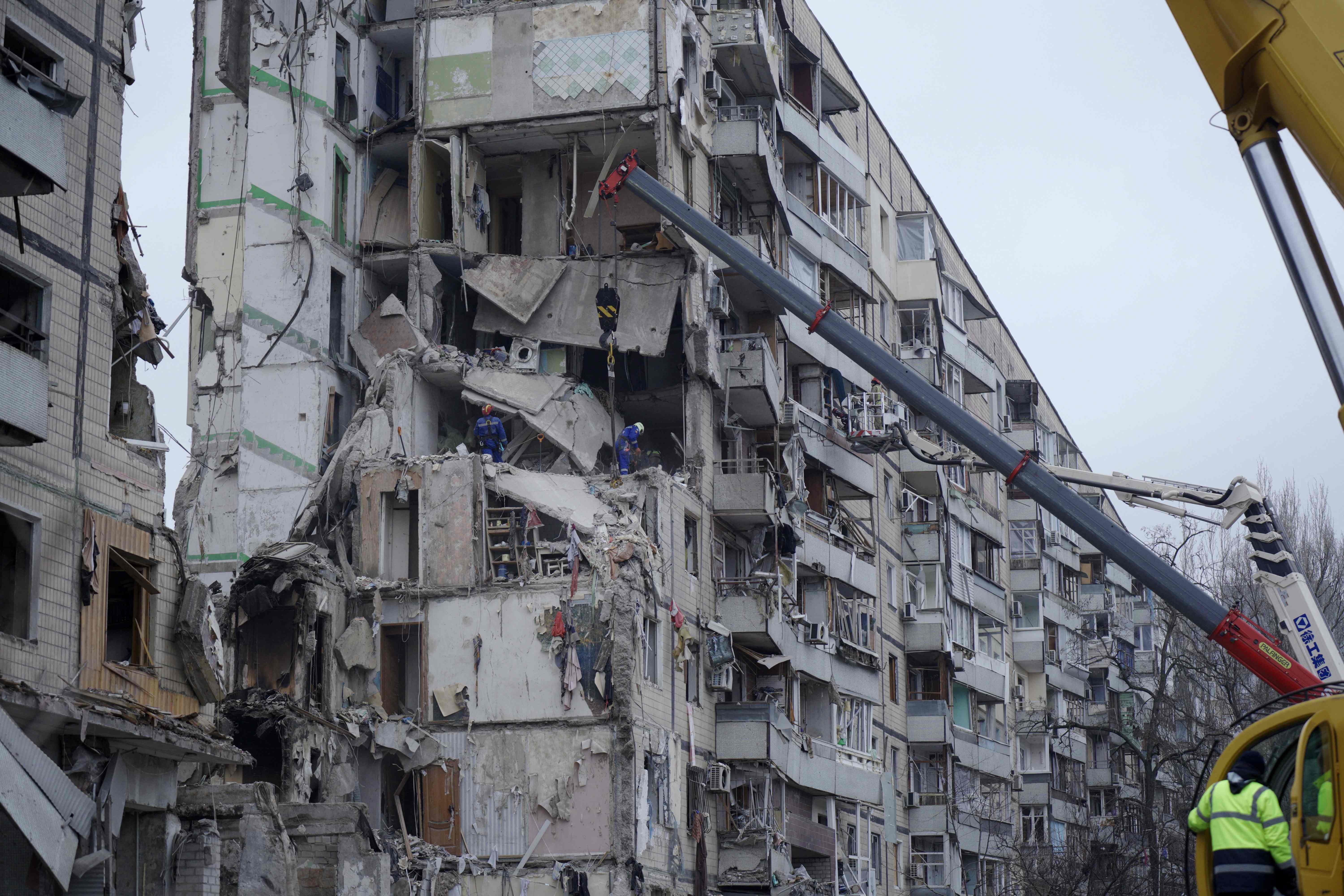 Rescuers work around the apartment building destroyed by a Russian missile strike