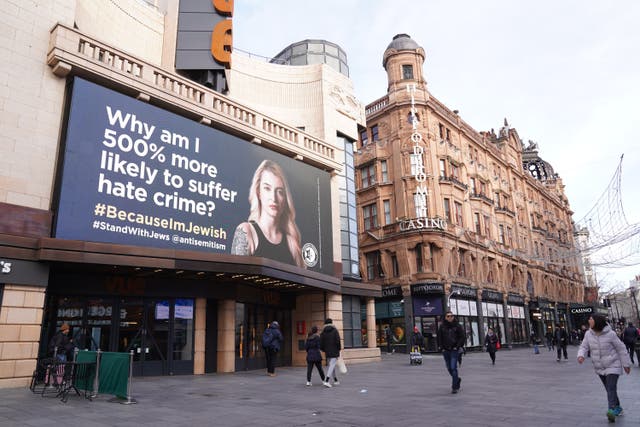 People walk past a billboard in Leicester Square, London (Kirsty O’Connor/PA)