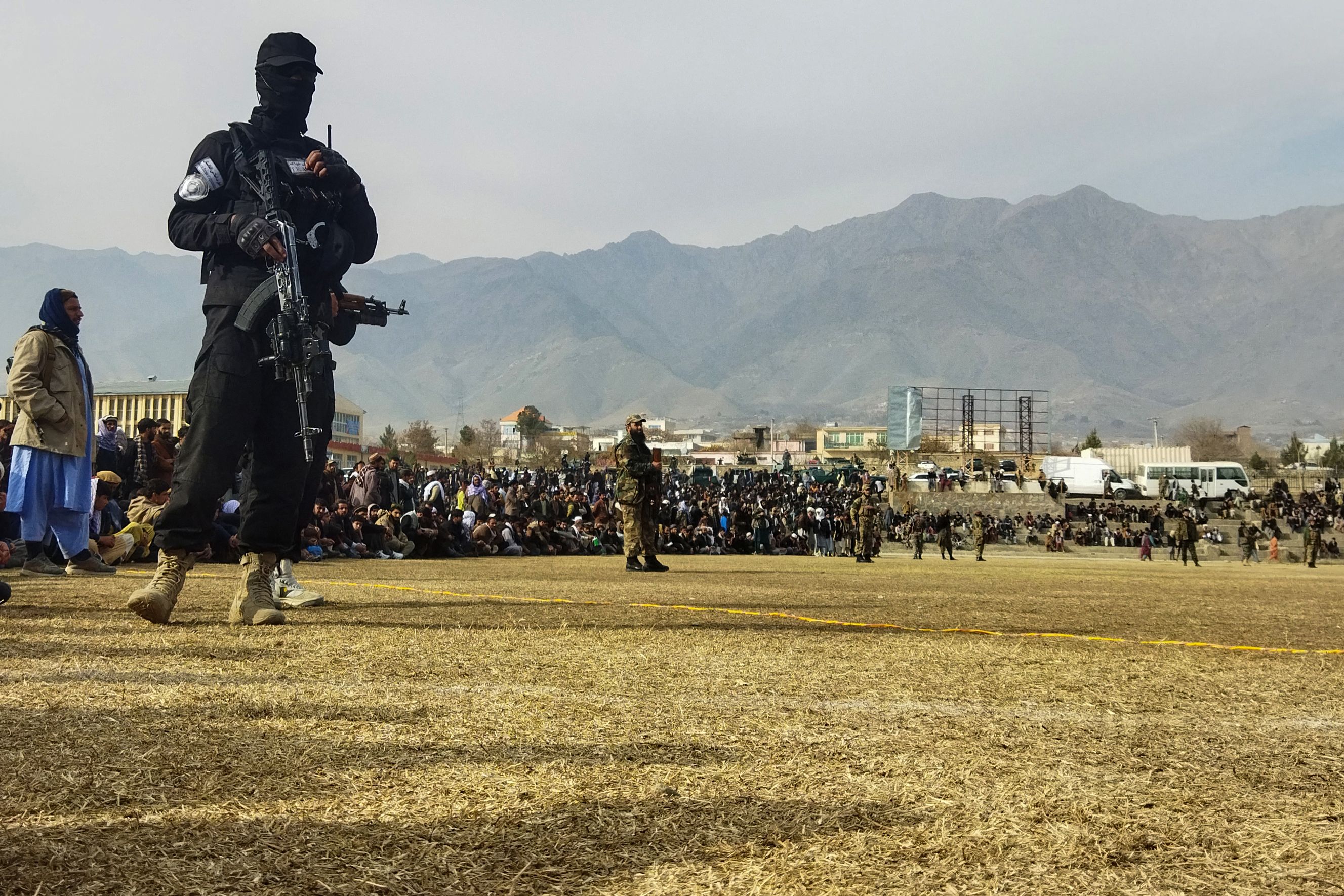 A Taliban security personnel stands guard as people attend to watch a public flogging of women and men at a football stadium in December
