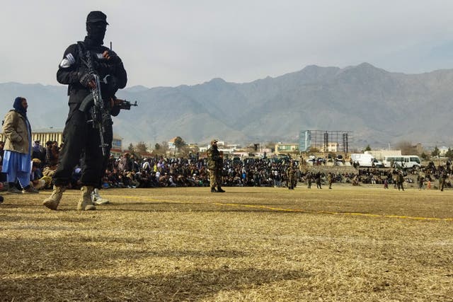 <p>A Taliban security personnel stands guard as people attend to watch a public flogging of women and men at a football stadium in December </p>