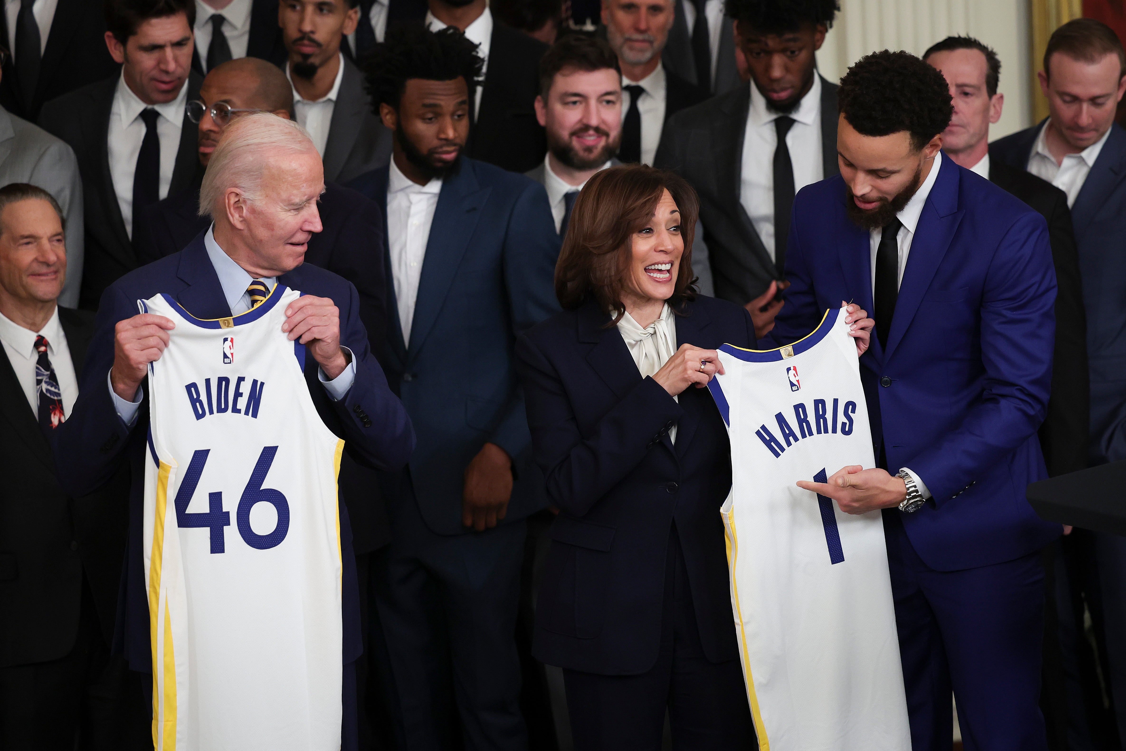 Steph Curry presents Joe Biden with a “46” jersey recognising the 46h president, while Vice President Kamala Harris receives a “1” jersey.