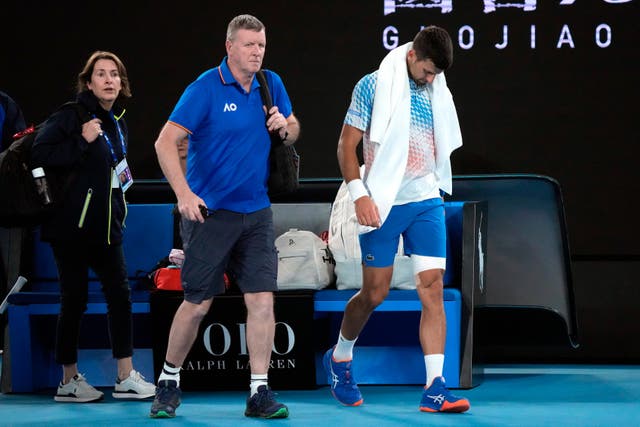 Novak Djokovic, right, leaves the court with the trainer (Dita Alangkara/AP)