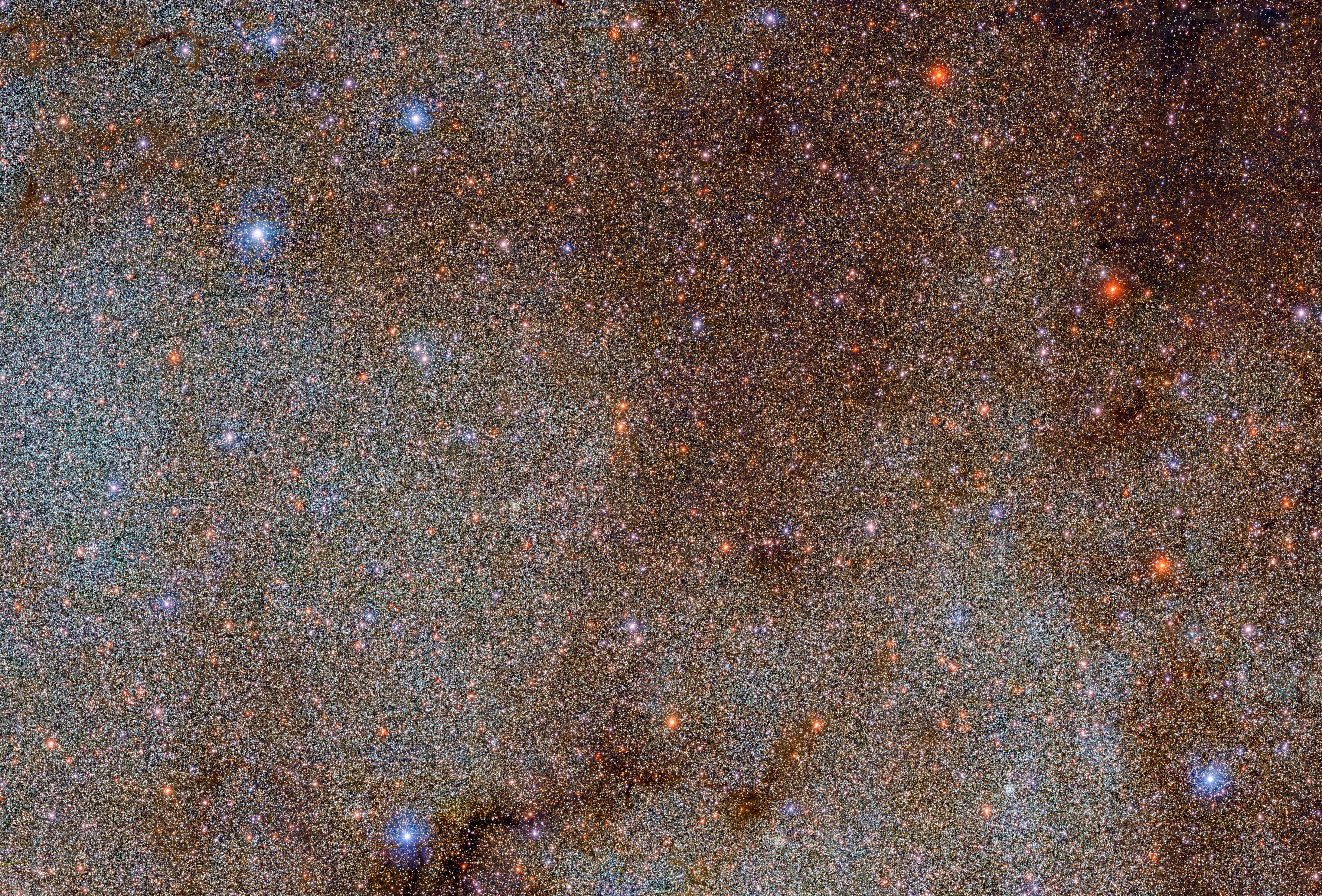 This image, which is brimming with stars and dark dust clouds, is a small extract — a mere pinprick — of the full Dark Energy Camera Plane Survey (DECaPS2) of the Milky Way