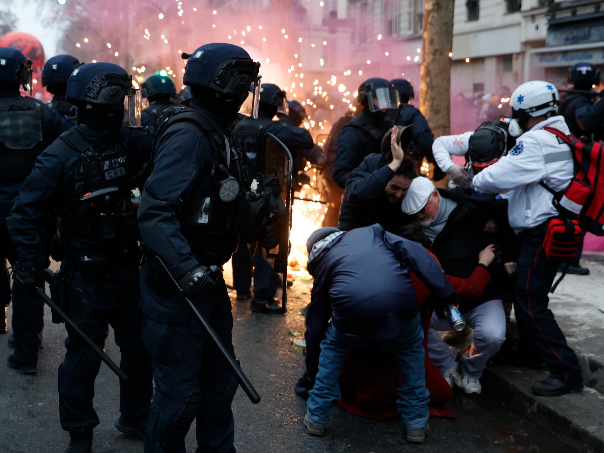 Demonstrators protect themselves near riot police officers in Paris