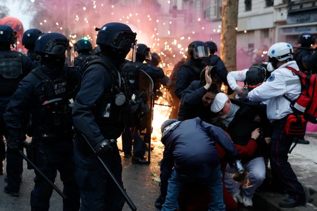 <p>Demonstrators protect themselves near riot police officers in Paris</p>